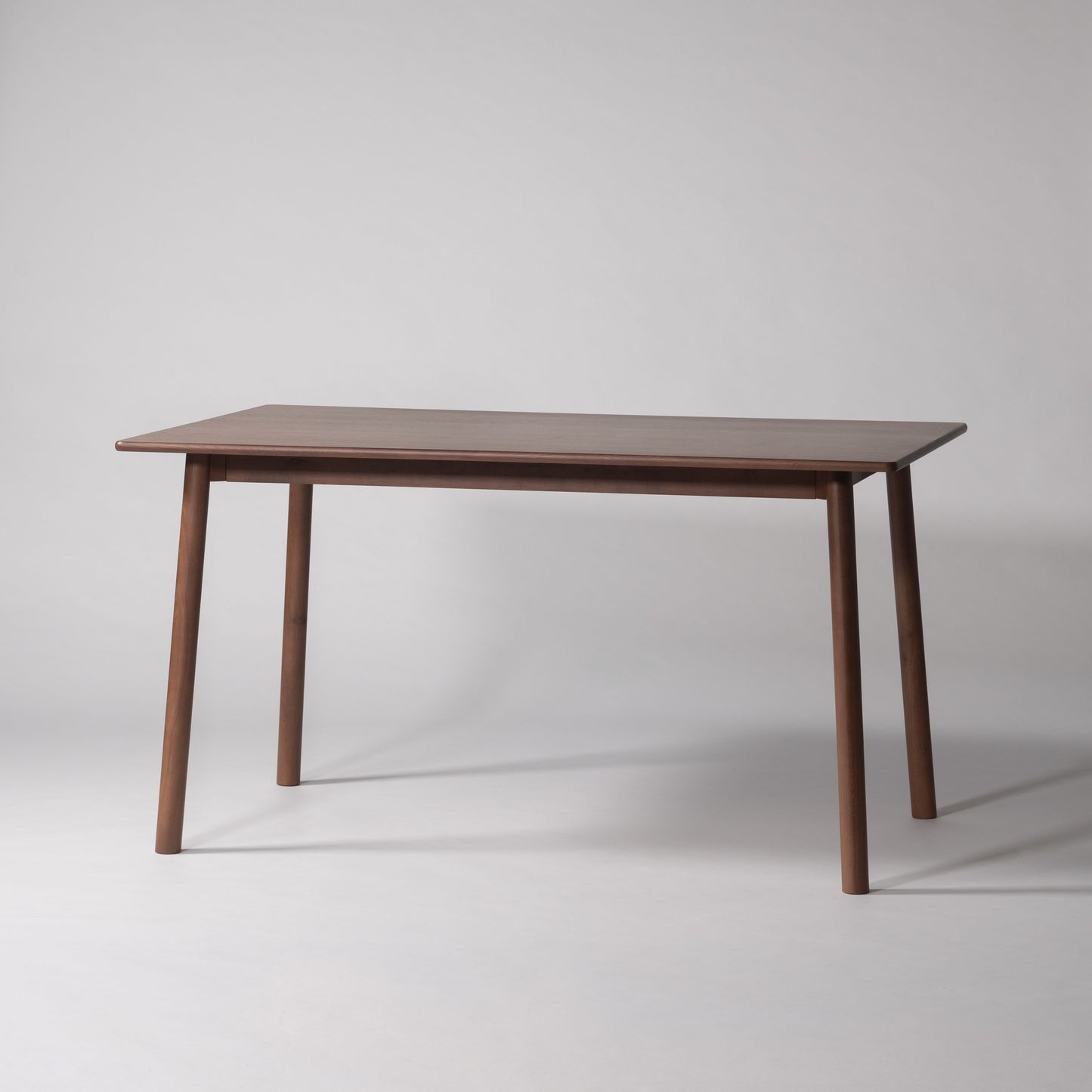 天然木オーク材を天板と脚部に使用しウレタン塗装で濃いブラウンに塗られたワントーンデザインのダイニングテーブル