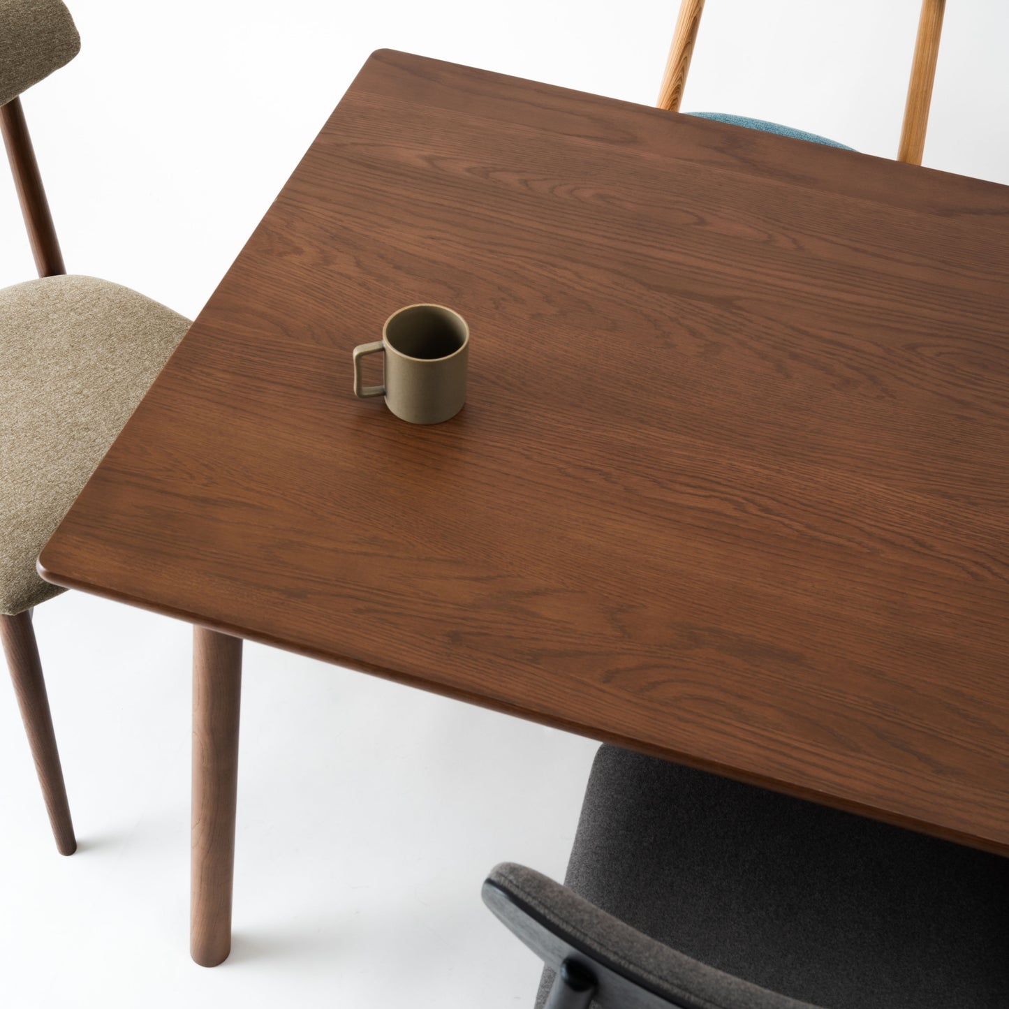 天然木オーク材を天板と脚部に使用しウレタン塗装で濃いブラウンに塗られたワントーンデザインのダイニングテーブルの天板のアップ