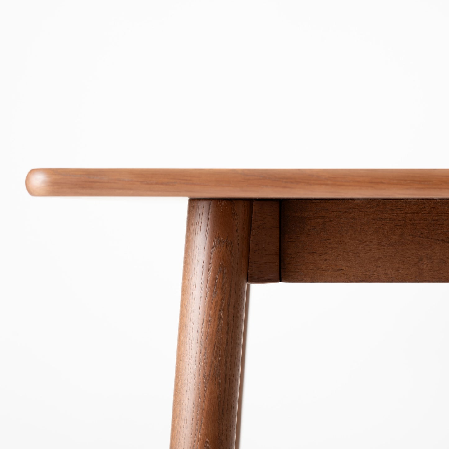 天然木オーク材を天板と脚部に使用しウレタン塗装で濃いブラウンに塗られたワントーンデザインのダイニングテーブルを真横から見た時の天板の写真