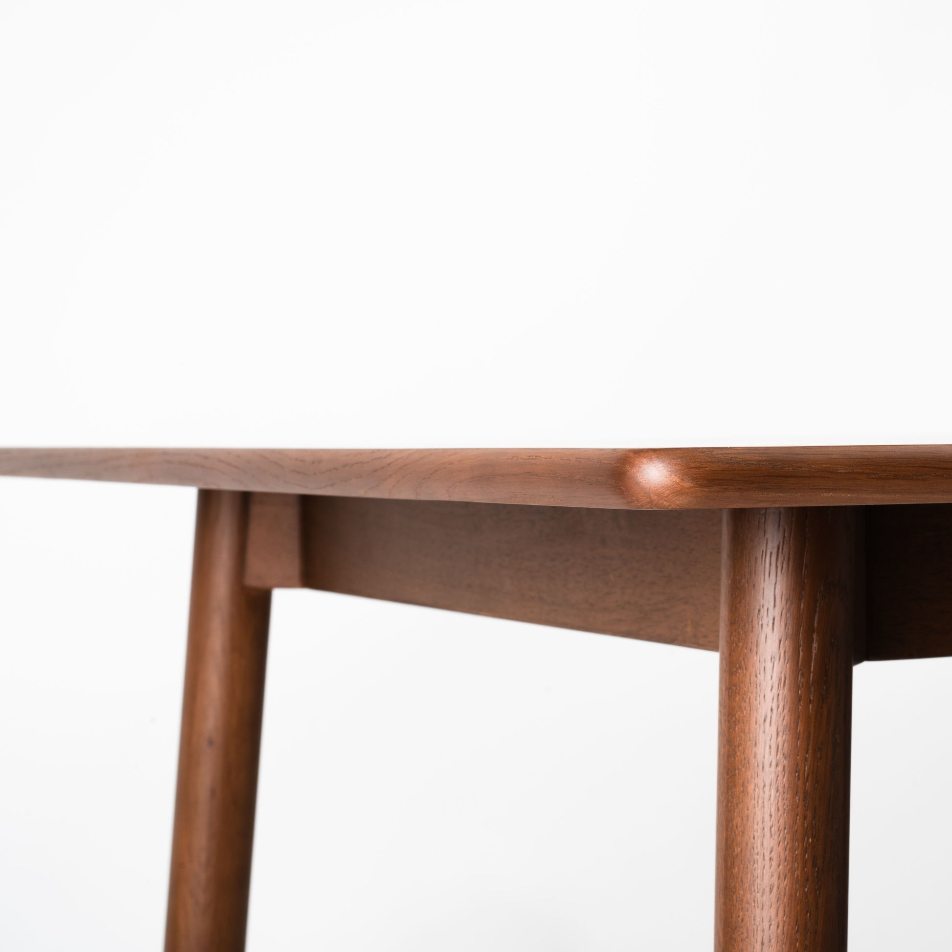 天然木オーク材を天板と脚部に使用しウレタン塗装で濃いブラウンに塗られたワントーンデザインのダイニングテーブルの天板の角の写真