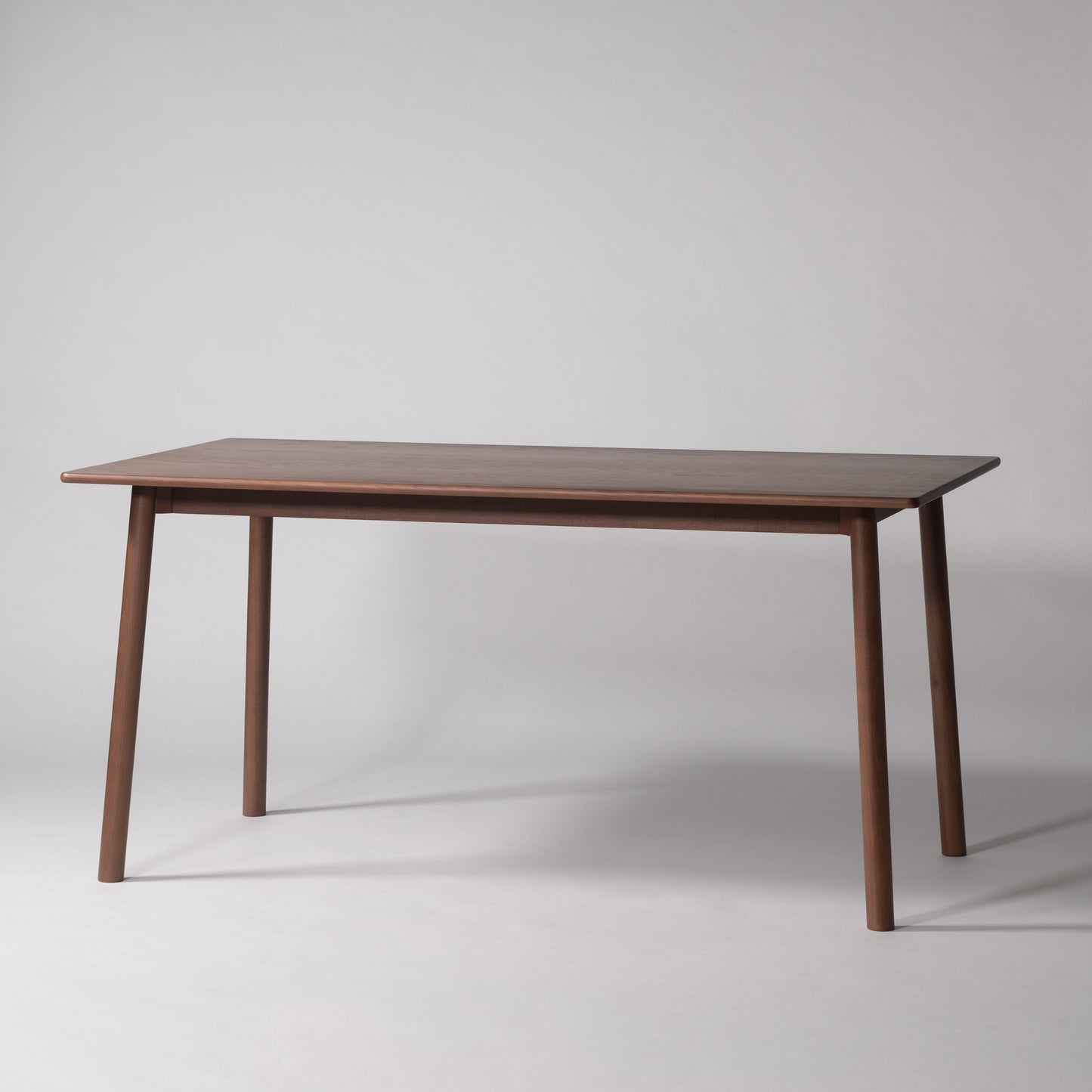 天然木オーク材を天板と脚部に使用しウレタン塗装で濃いブラウンに塗られたワントーンデザインのダイニングテーブル