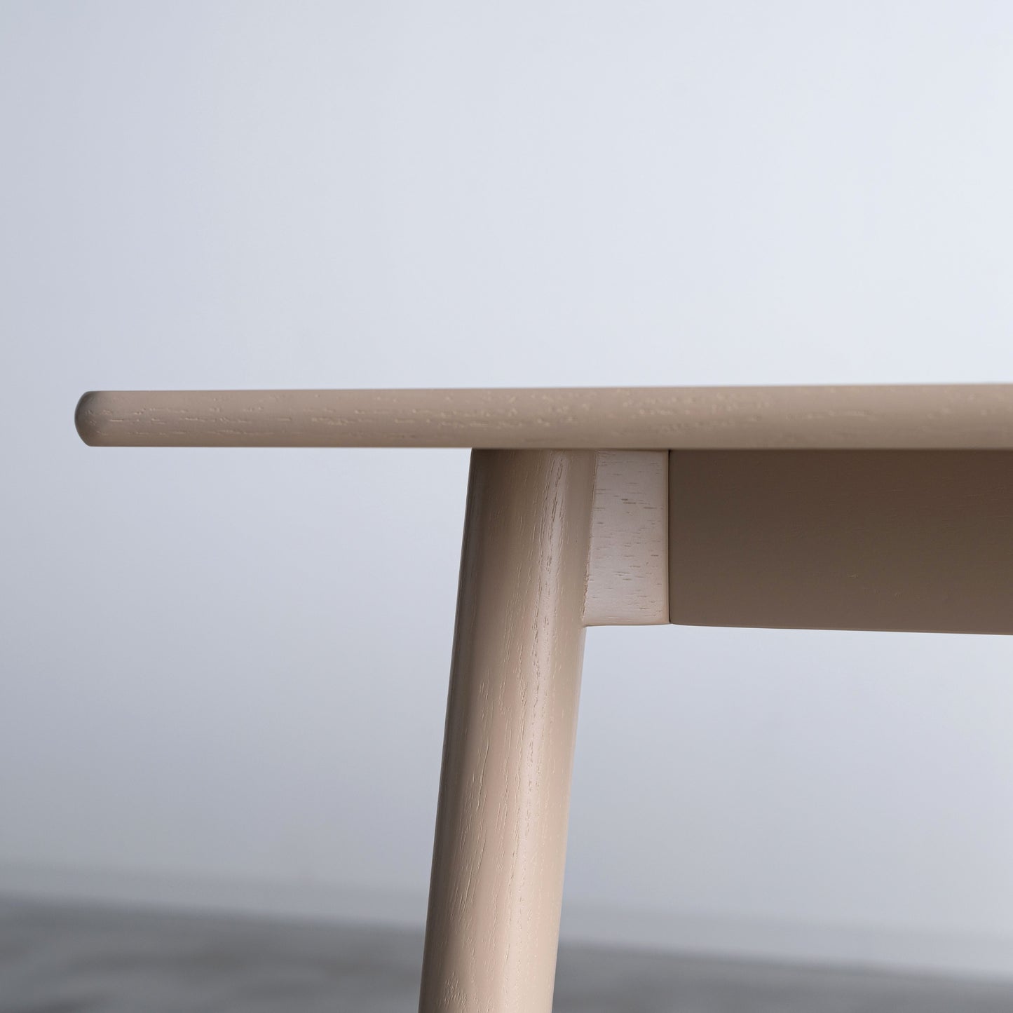 天然木オーク材を天板と脚部に使用しウレタン塗装でグレーに塗られたワントーンデザインのダイニングテーブルの天板を真横から見た写真