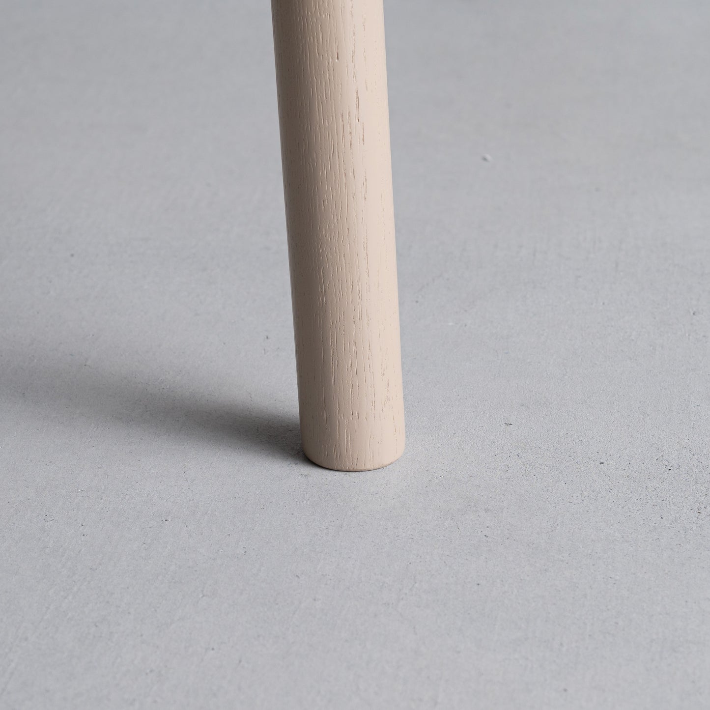 天然木オーク材を天板と脚部に使用しウレタン塗装でグレーに塗られたワントーンデザインのダイニングテーブルの足のアップ