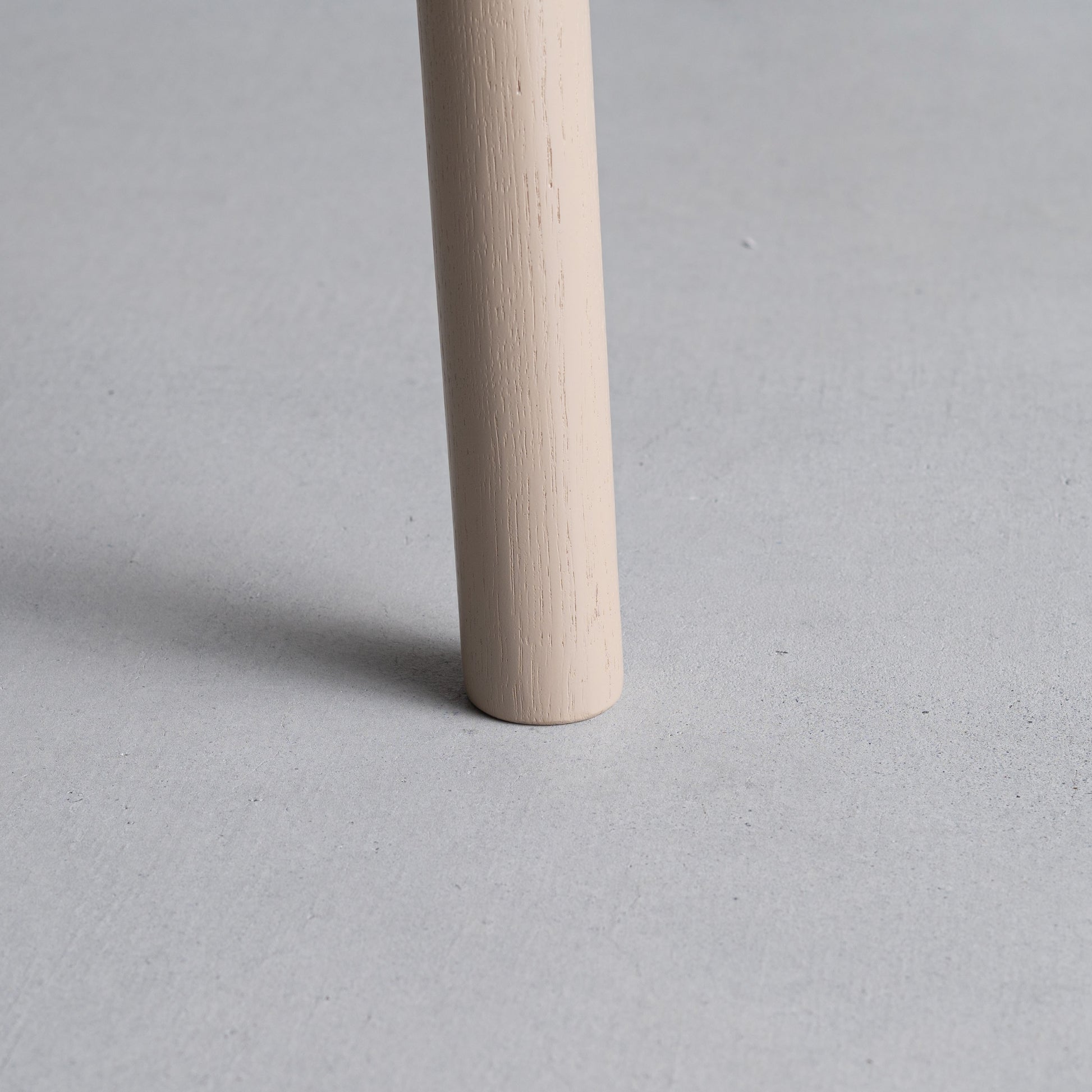 天然木オーク材を天板と脚部に使用しウレタン塗装でグレーに塗られたワントーンデザインのダイニングテーブルの足のアップ