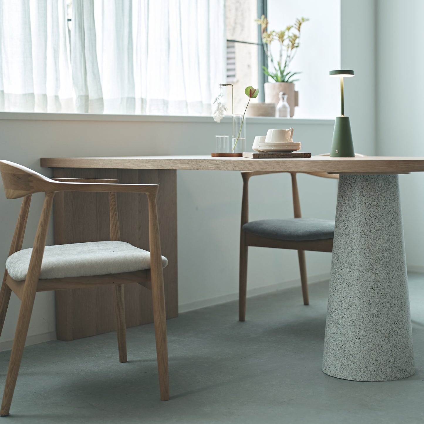 部屋の窓辺で天然木の天板にテラゾー柄のスチール脚を組み合わせた、異素材ミックスデザインのダイニングテーブルと天然木のダイニングチェアを合わせたインテリア