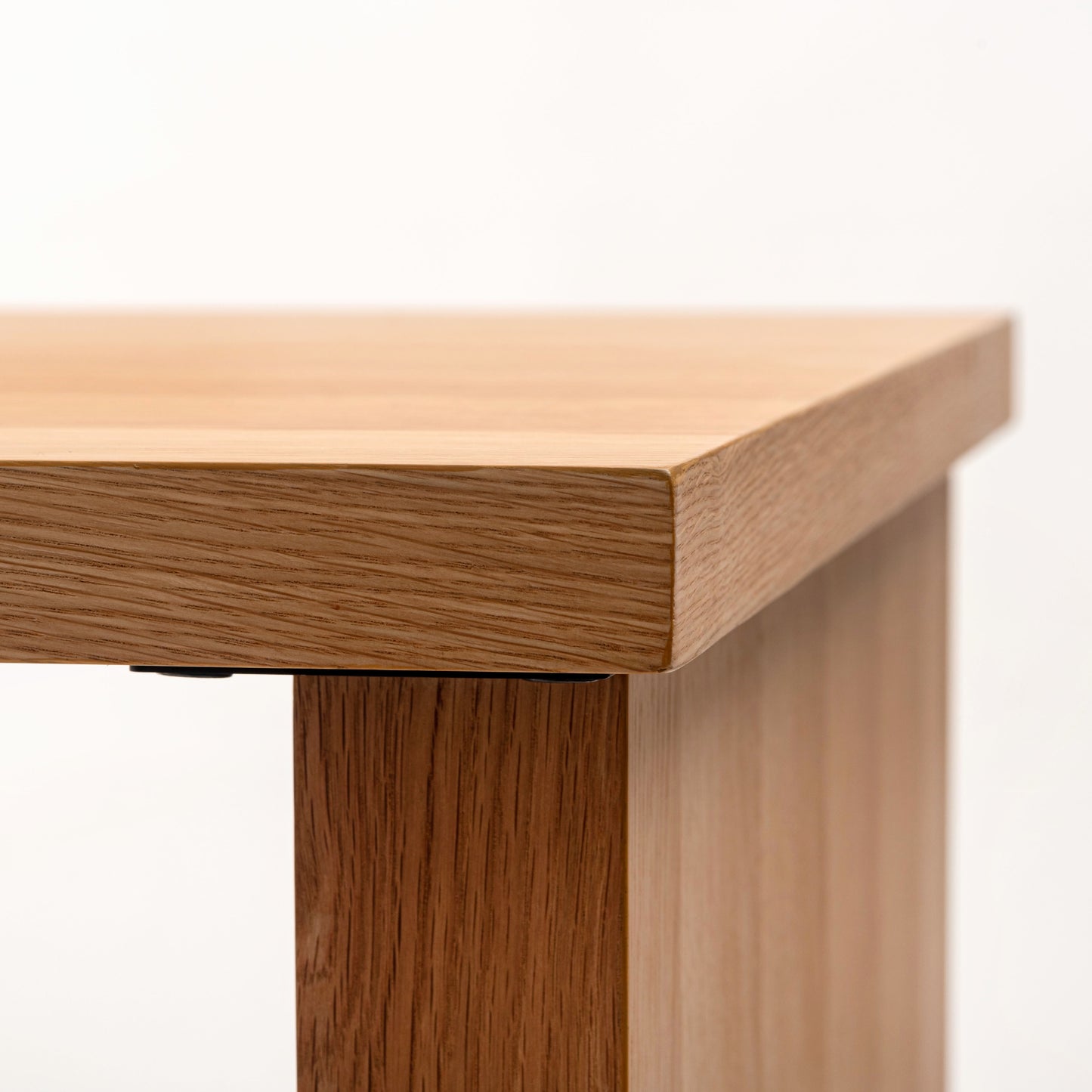 天然木の天板にテラゾー柄のスチール脚を組み合わせた、異素材ミックスデザインのダイニングテーブルの天板の角の部分のアップ