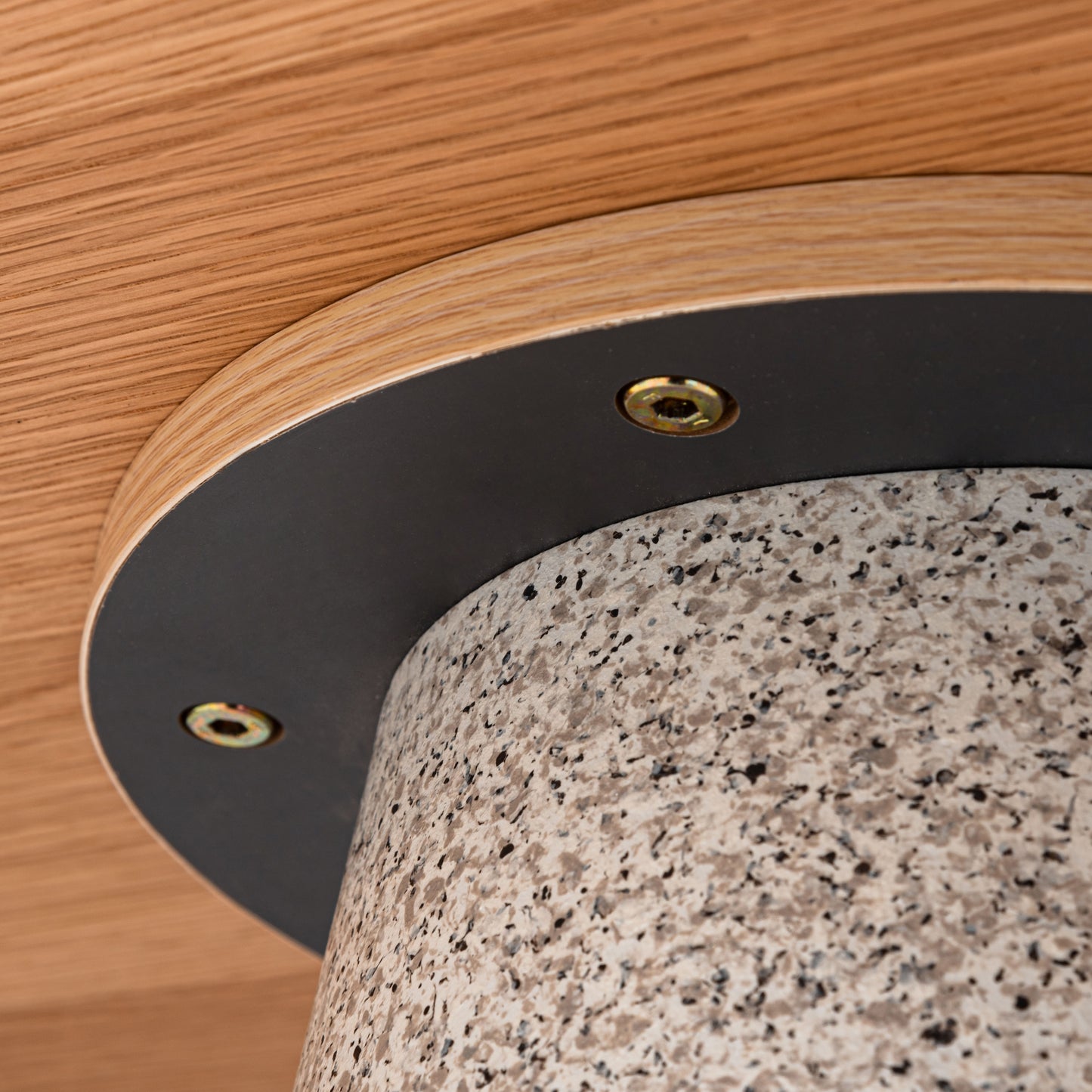 天然木の天板にテラゾー柄のスチール脚を組み合わせた、異素材ミックスデザインのダイニングテーブルの天板の裏側の足とのせつ足との接続部分の留め具のアップ