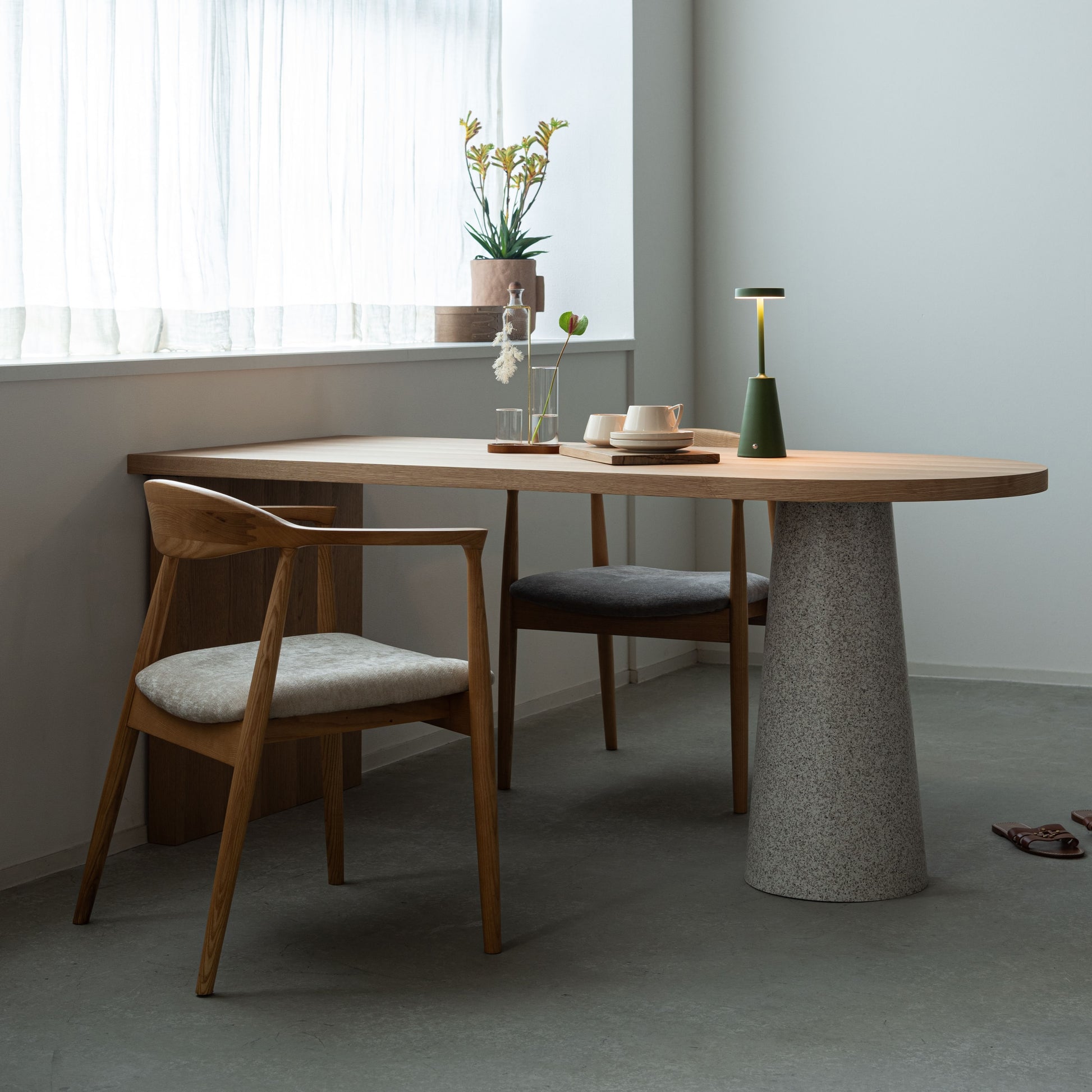 部屋の窓辺で天然木の天板にテラゾー柄のスチール脚を組み合わせた、異素材ミックスデザインのダイニングテーブルと天然木のダイニングチェアを合わせたインテリア