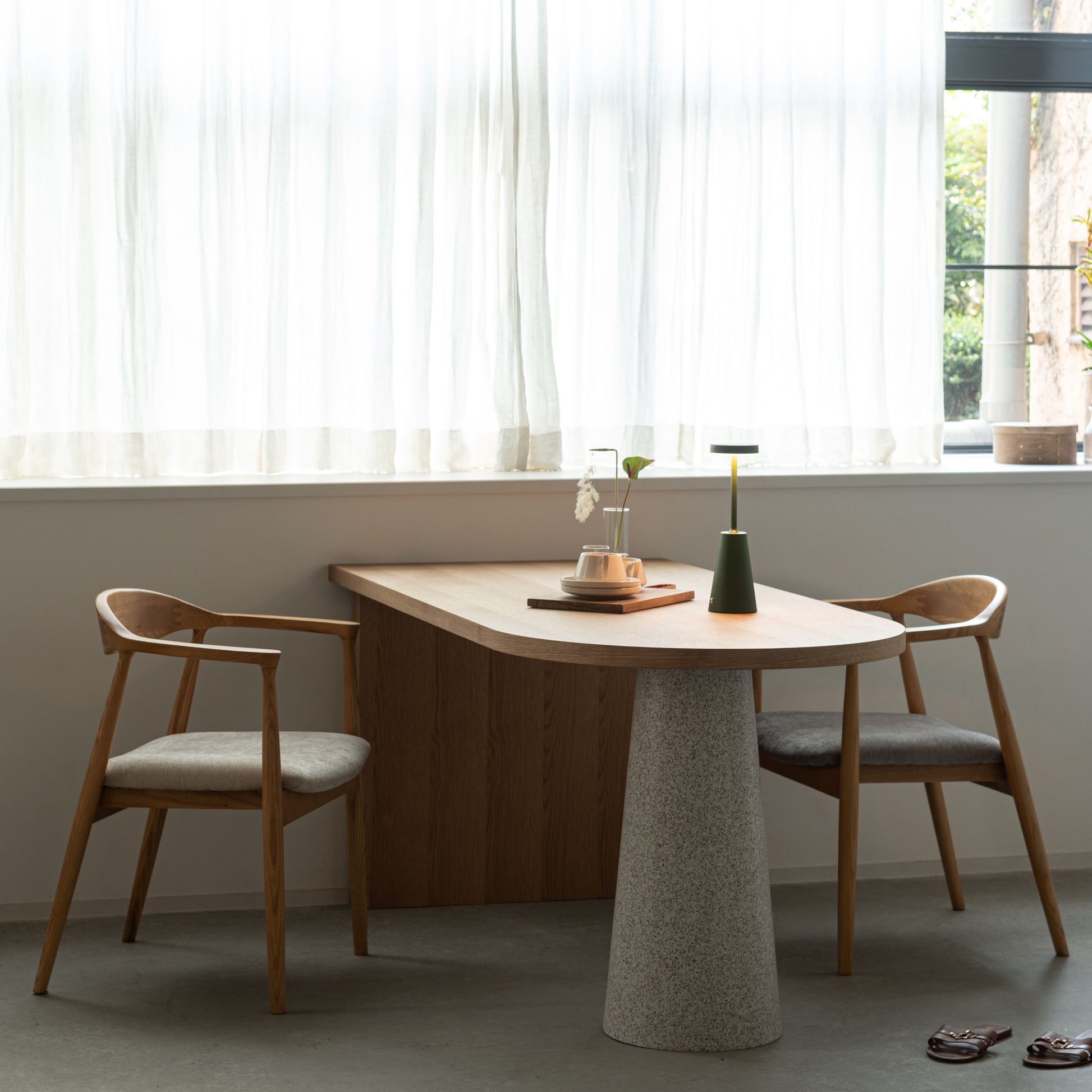 部屋の窓辺で天然木の天板にテラゾー柄のスチール脚を組み合わせた、異素材ミックスデザインのダイニングテーブルと天然木のダイニングチェアを合わせたインテリア