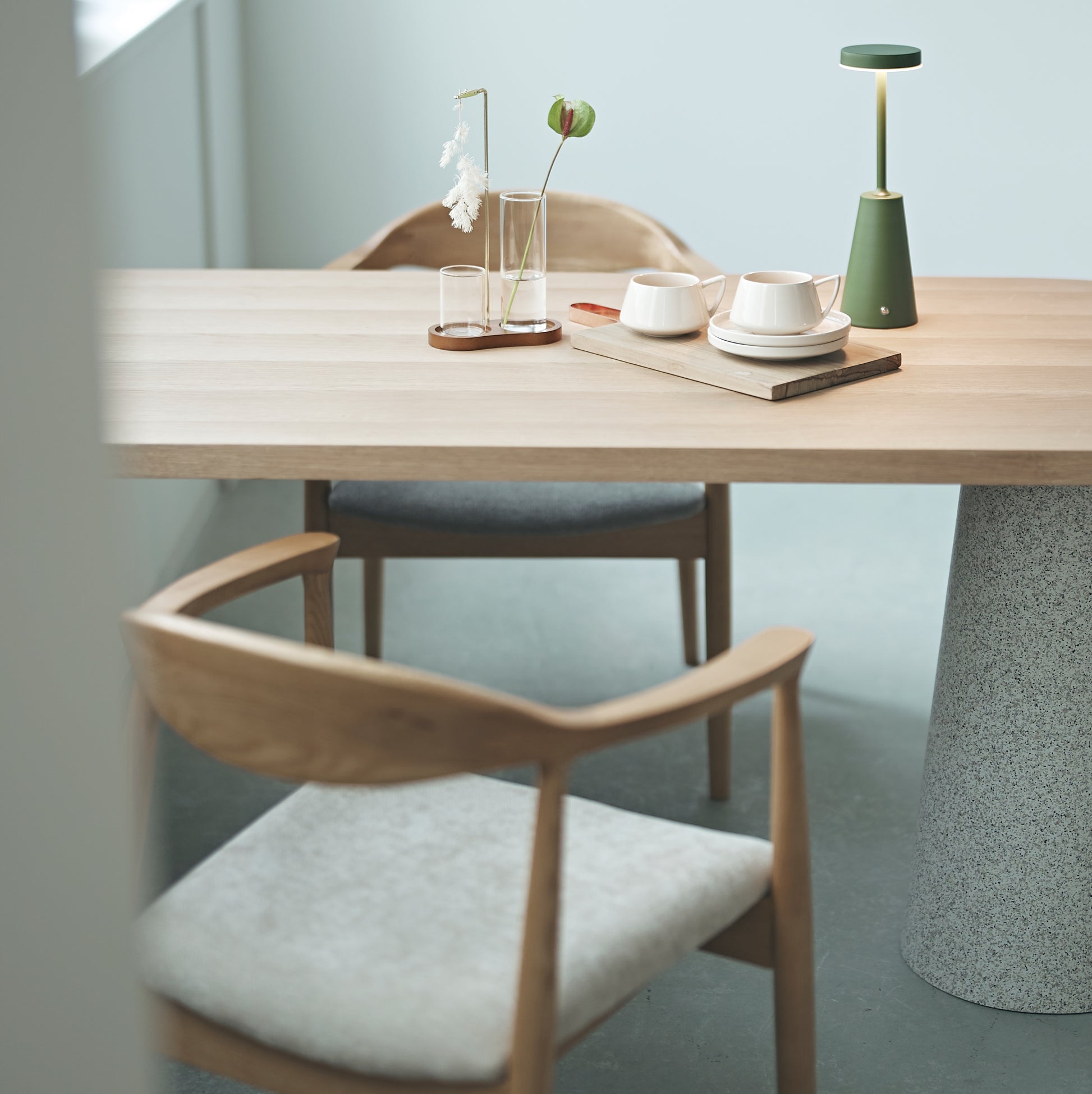 部屋の窓辺で天然木の天板にテラゾー柄のスチール脚を組み合わせた、異素材ミックスデザインのダイニングテーブルと天然木のダイニングチェアを合わせたインテリア