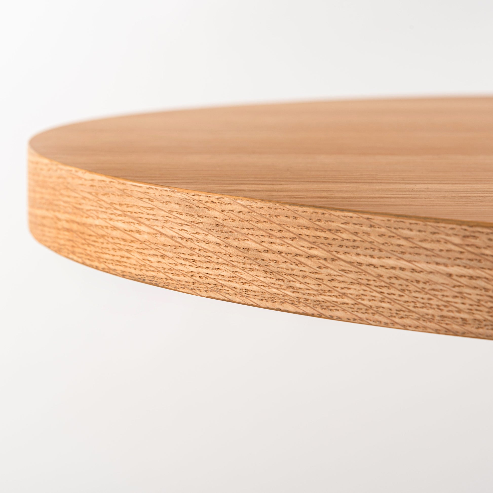 天然木の天板にテラゾー柄のスチール脚を組み合わせた、異素材ミックスデザインのダイニングテーブルの天板のカーブの部分のアップ