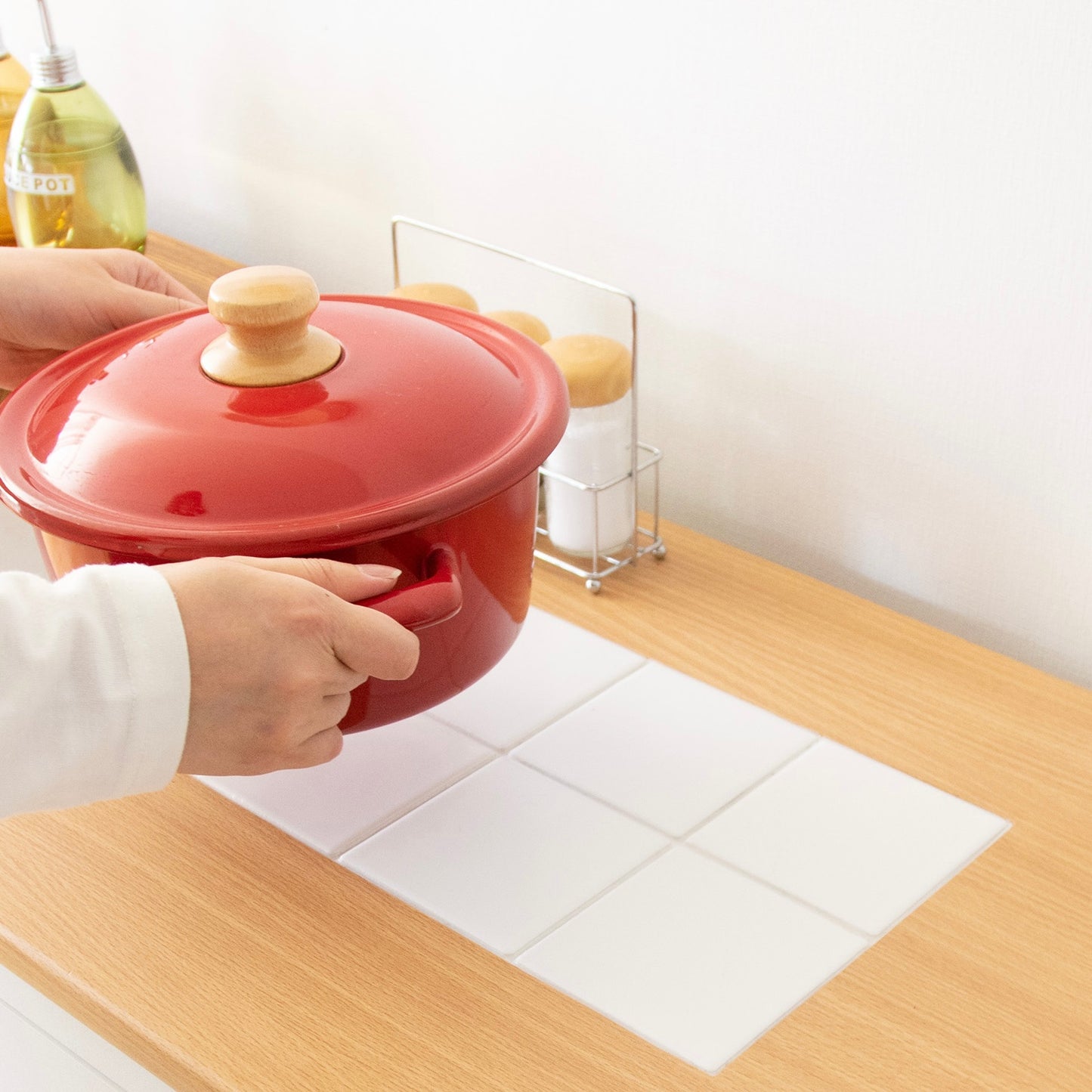 キャスター付きコンパクトキッチンチェストの上に赤い木製蓋の取っ手と両側取っ手付きの陶器鍋