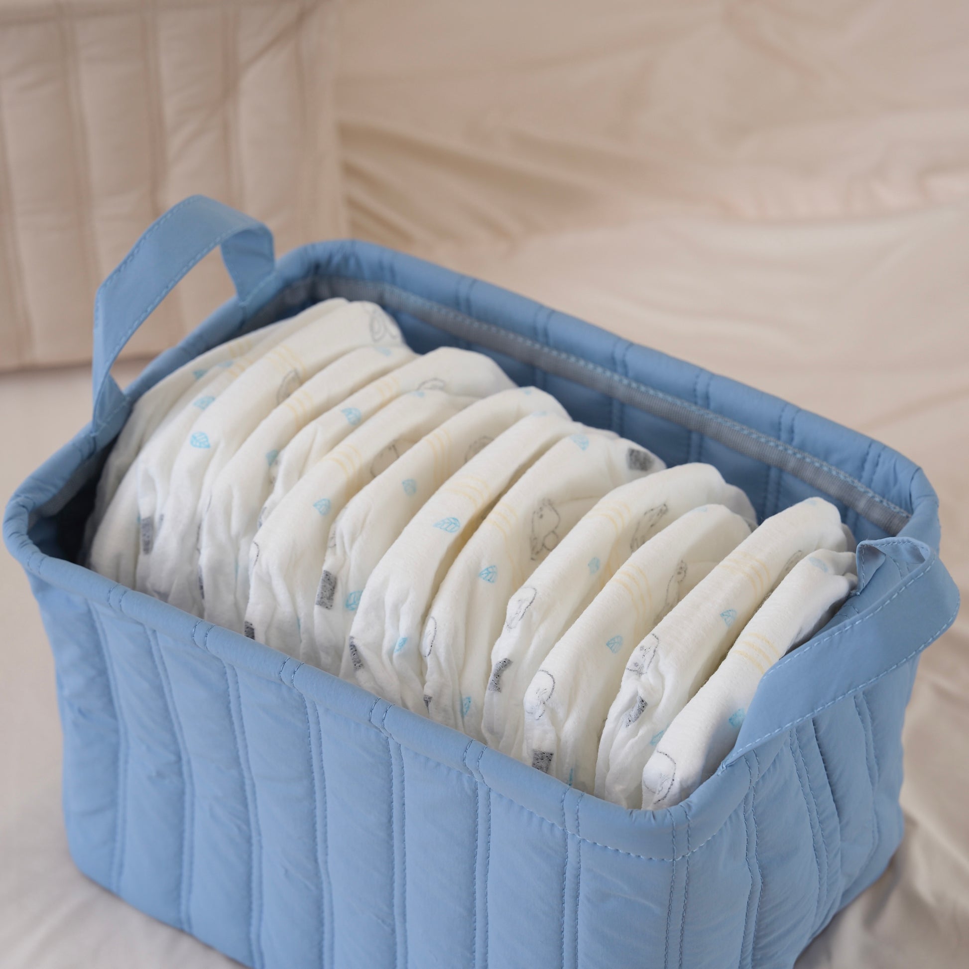 キルティング素材のブルーのバスケットにオムツが収納されている様子