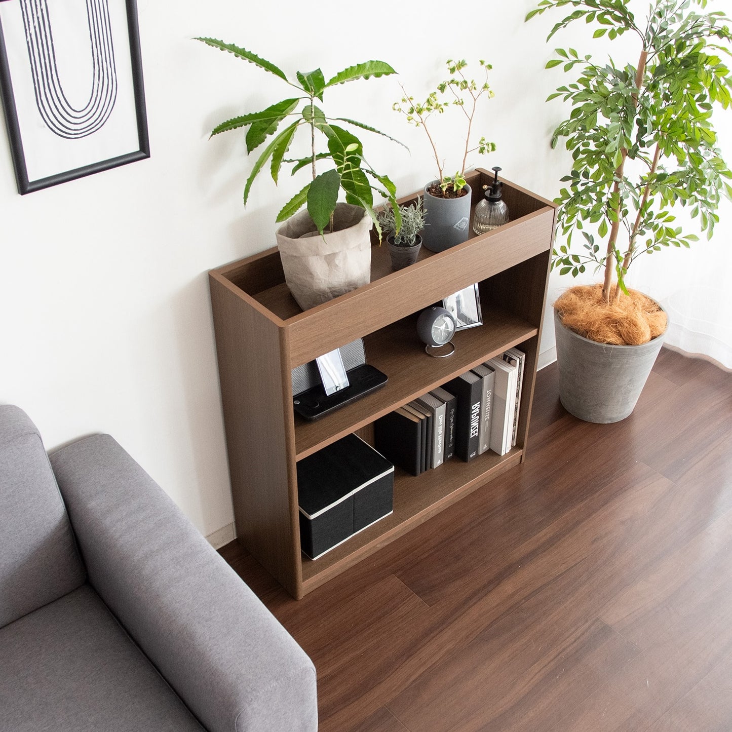 ブラウンの2段のオープンラックに植物と本が収納されている様子