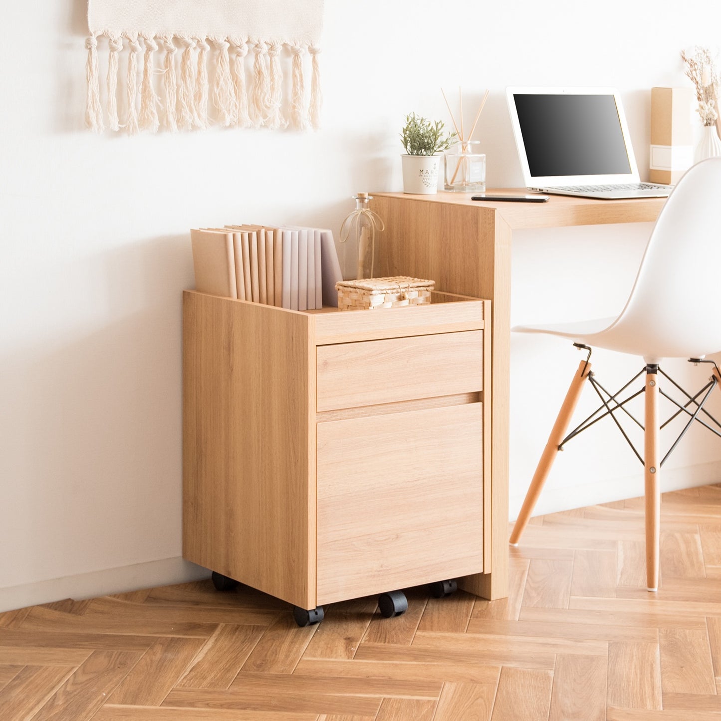 デスク横に置かれた木目調のサイドチェストに本が収納されている様子