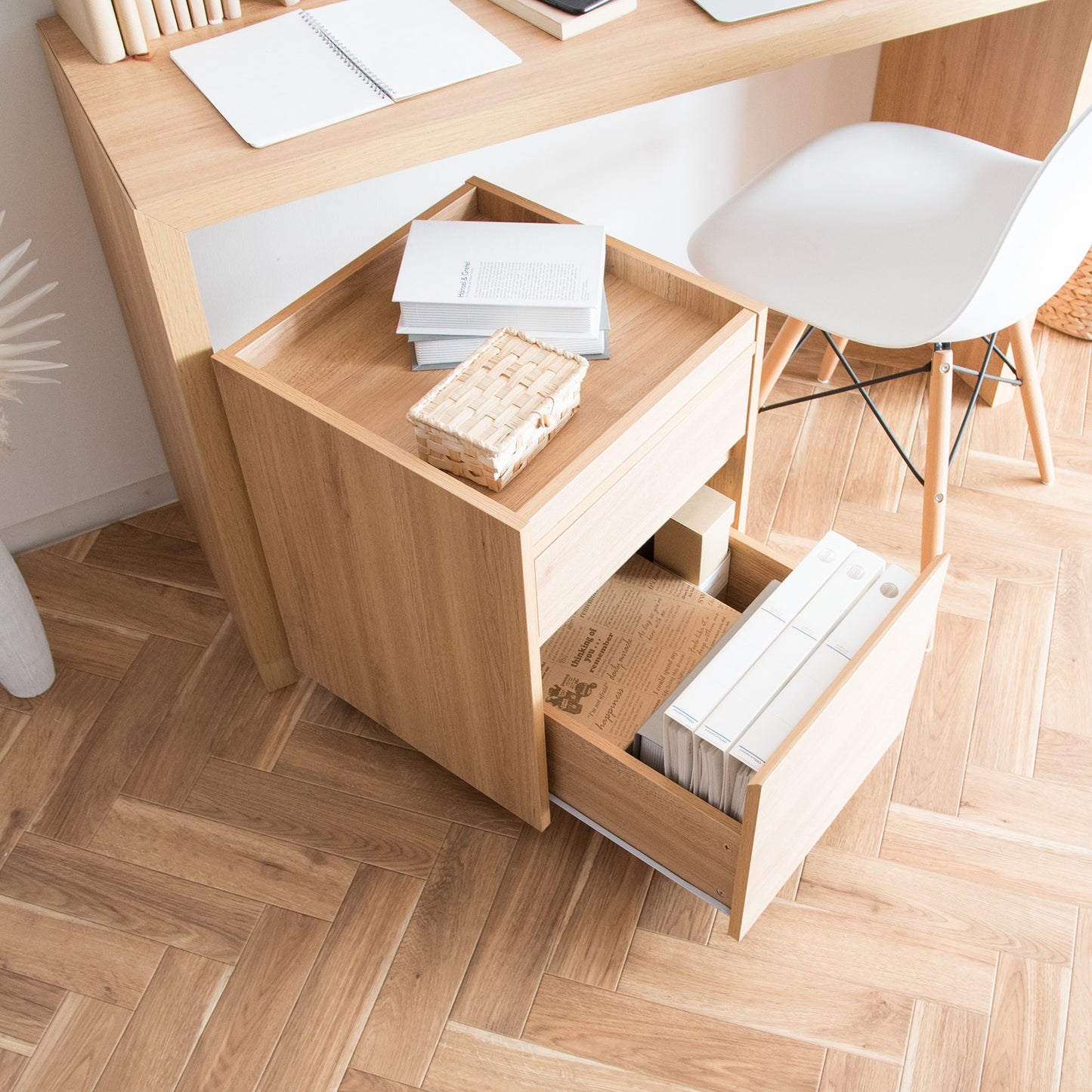 デスク横に置かれた木目調のサイドチェストに書類や本が収納されている様子