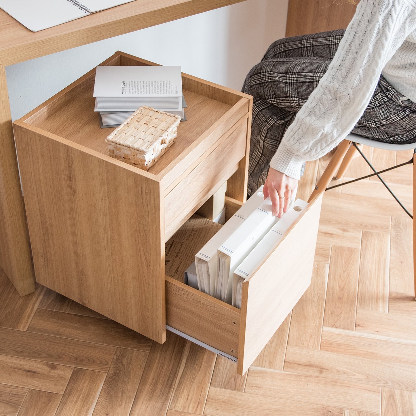 デスク下に置かれた木目調のサイドチェストから書類を取り出そうとしている様子