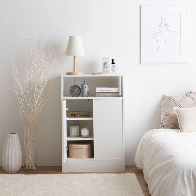 白の扉付きの収納とオープン棚が組み合わさったキャビネットを部屋の中でベッドの横に置いている