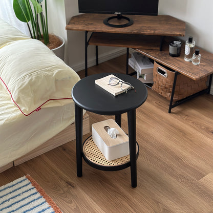 黒の２段のラタン風サイドテーブルにメガネと文庫本、ティッシュケースが置かれてある様子