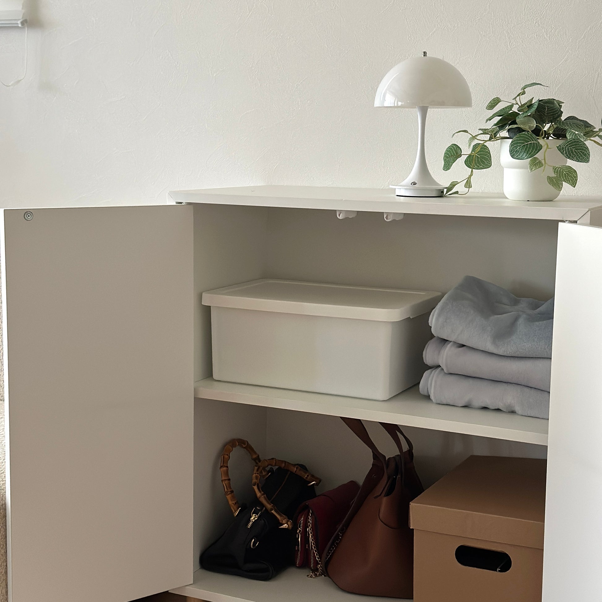 蓋付きのシンプルなプラスチックの収納ボックスが棚の中に収納されている様子