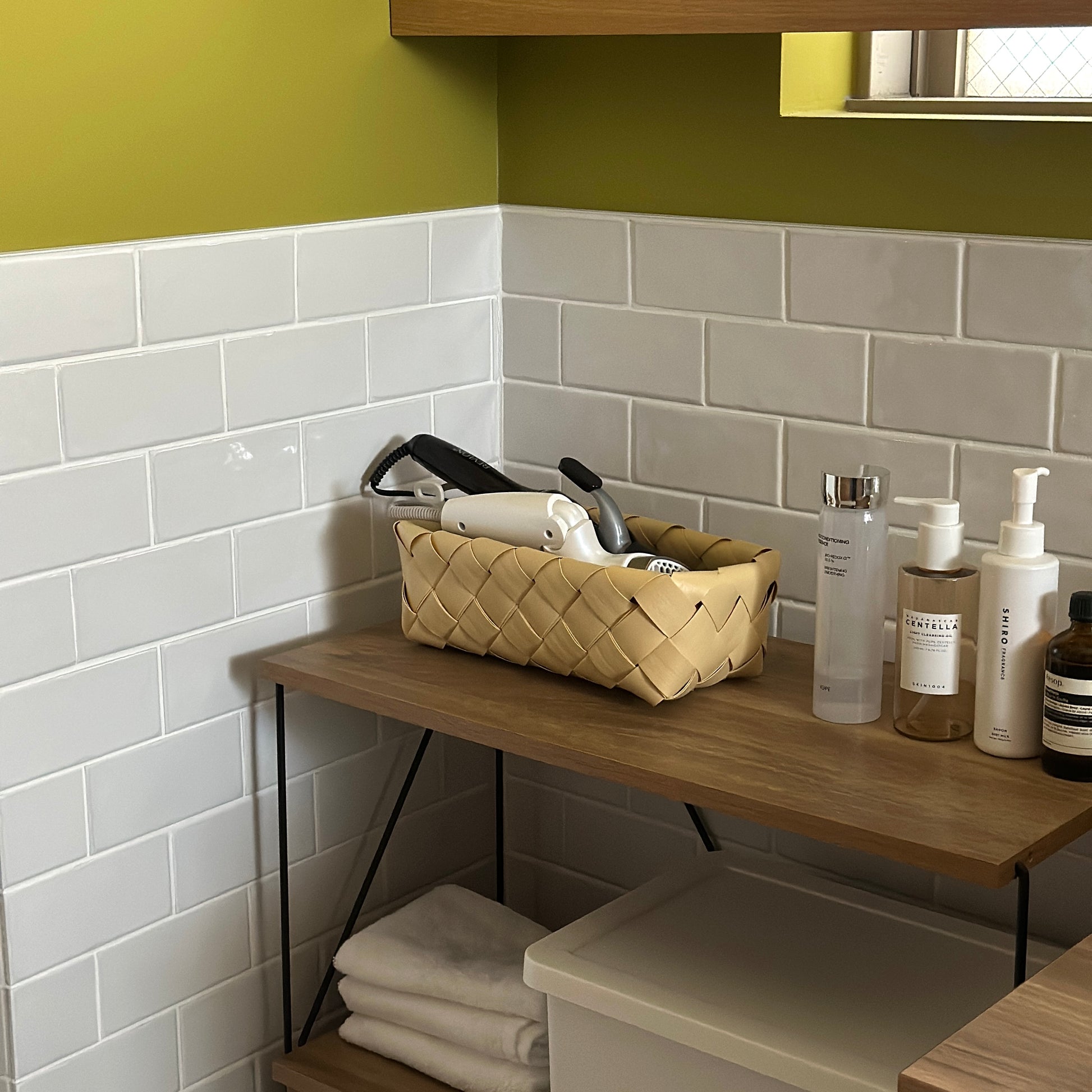 洗面所で手編みのバスケットにドライヤーやコテが収納されている様子