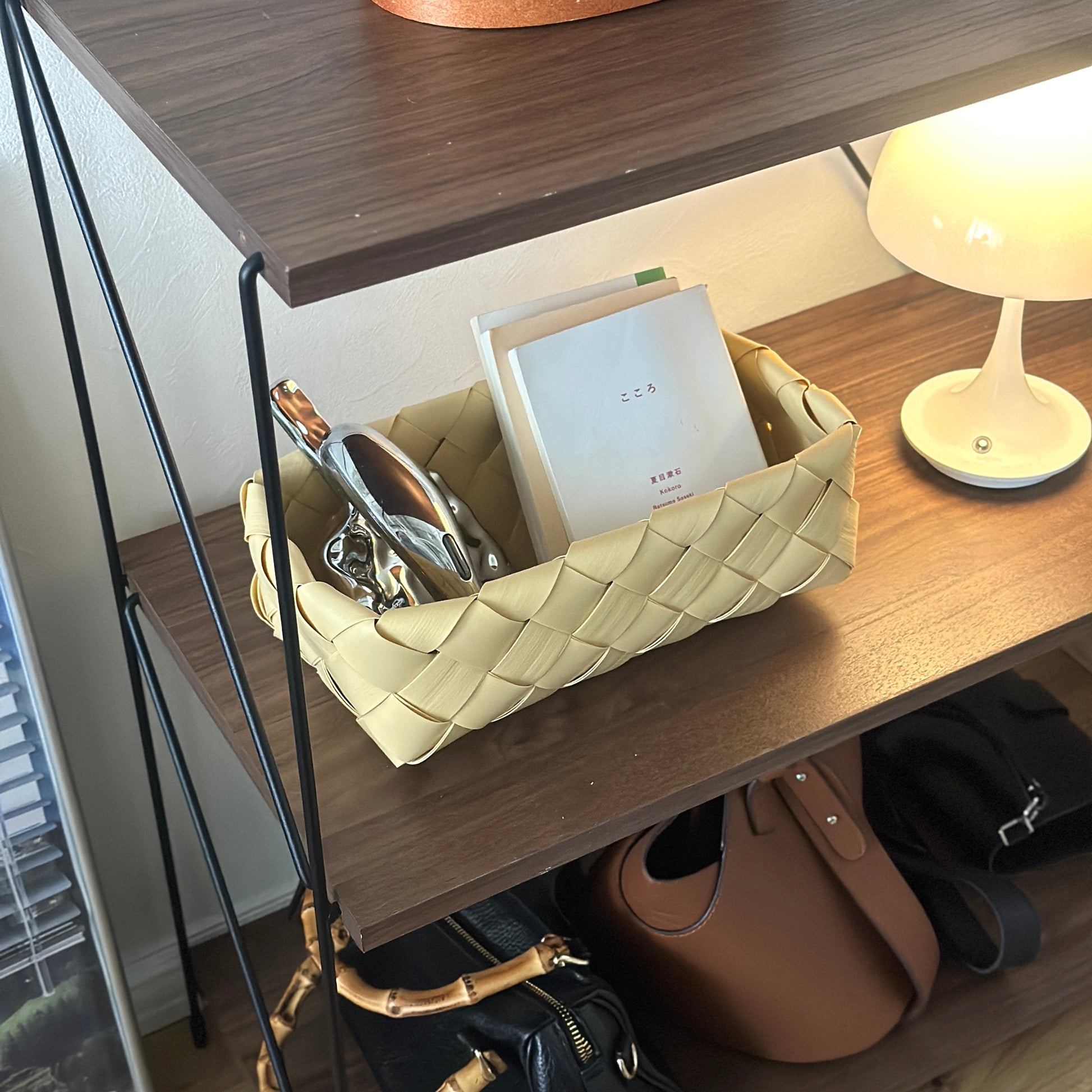 手編みのバスケットに本や小物が収納されている様子