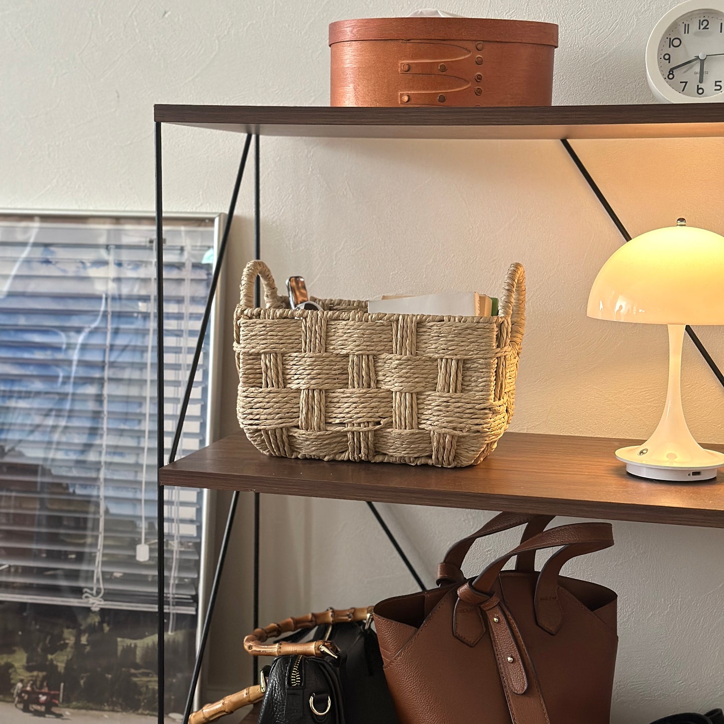 取手がついたロープ編みのバスケットに本や小物が収納されている様子