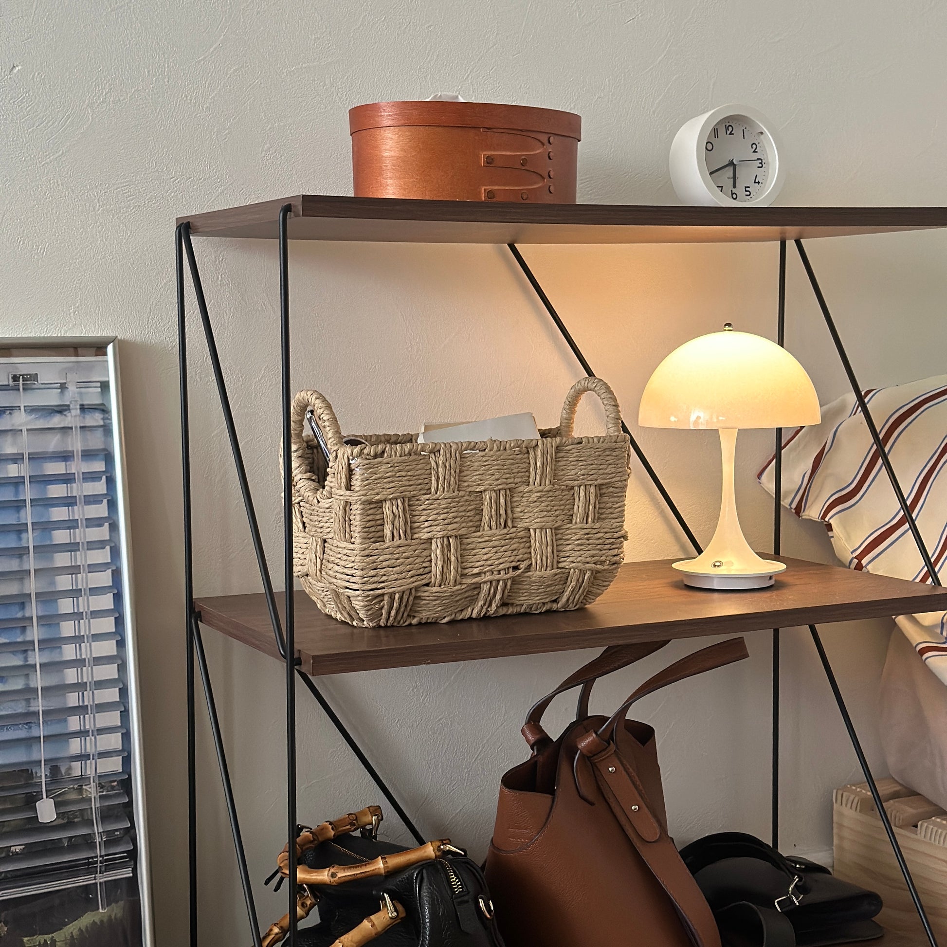 取手がついたロープ編みのバスケットに本や小物が収納されている様子