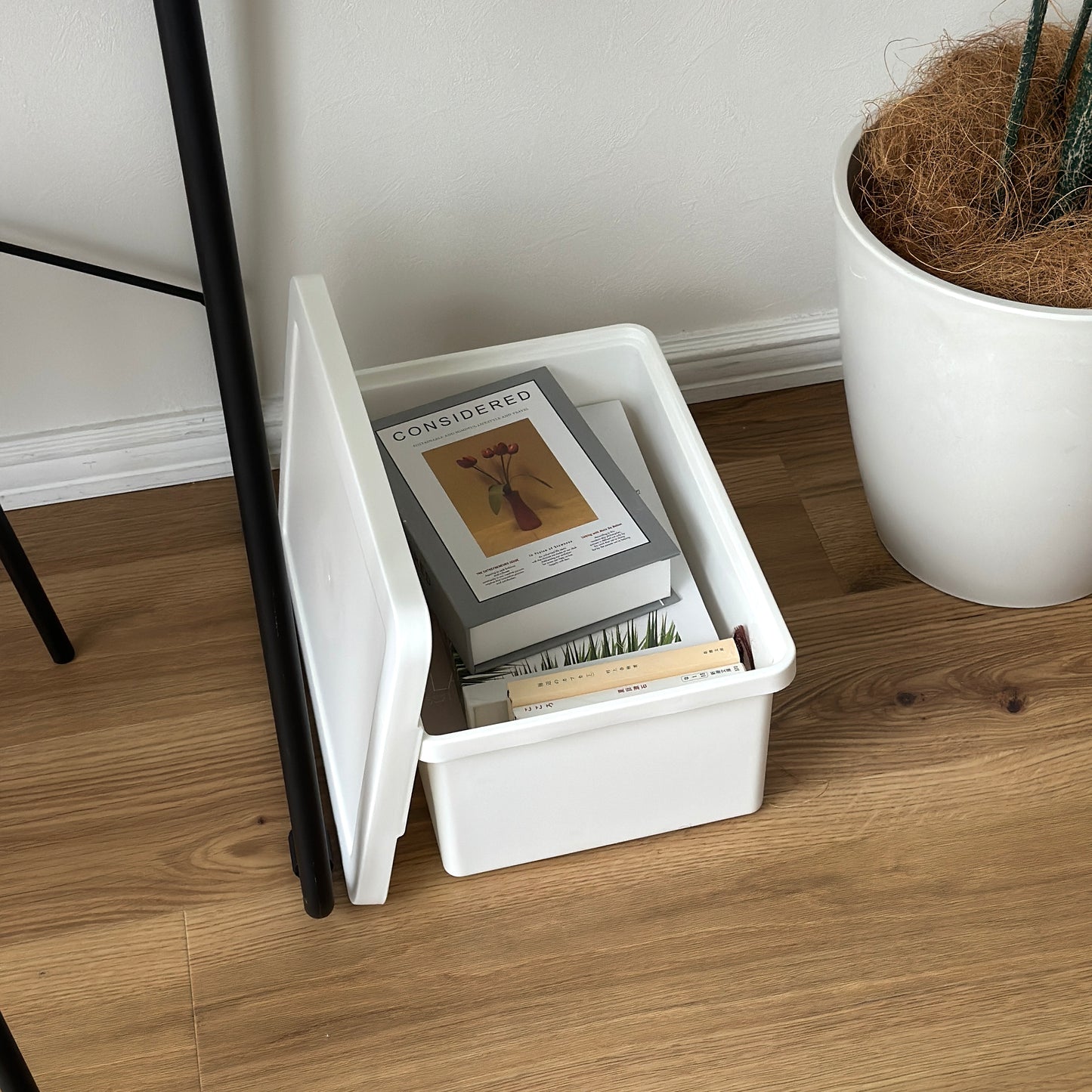 蓋付きのシンプルなプラスチックの収納ボックスの中に本が収納されている様子