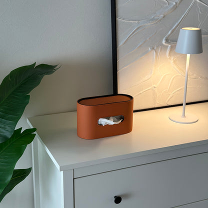 棚の上に置いてあるオレンジのレザー調デザインの楕円型ティッシュケース