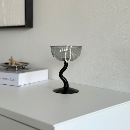 ウェーブの脚がついたガラスのマルチカップにアクセサリーが入っている様子