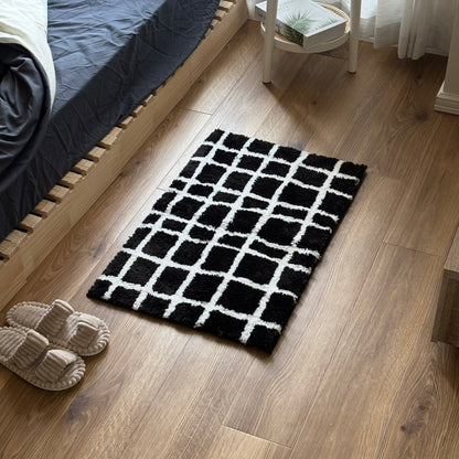 モノクロのチェック柄のミニラグをベッドの前に敷いている様子