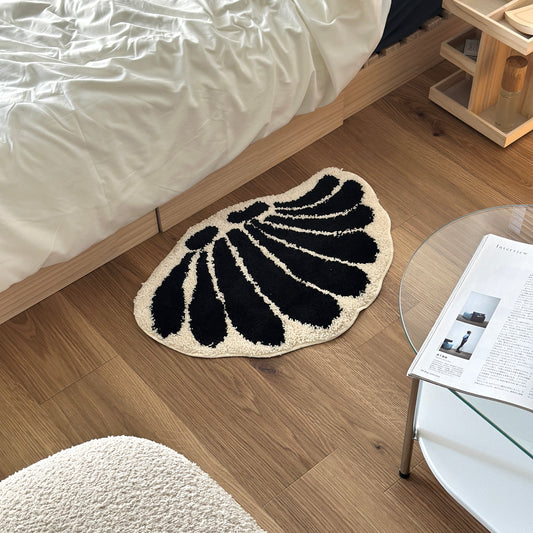 モノクロの貝殻柄のミニラグをベッドサイドに置いている様子