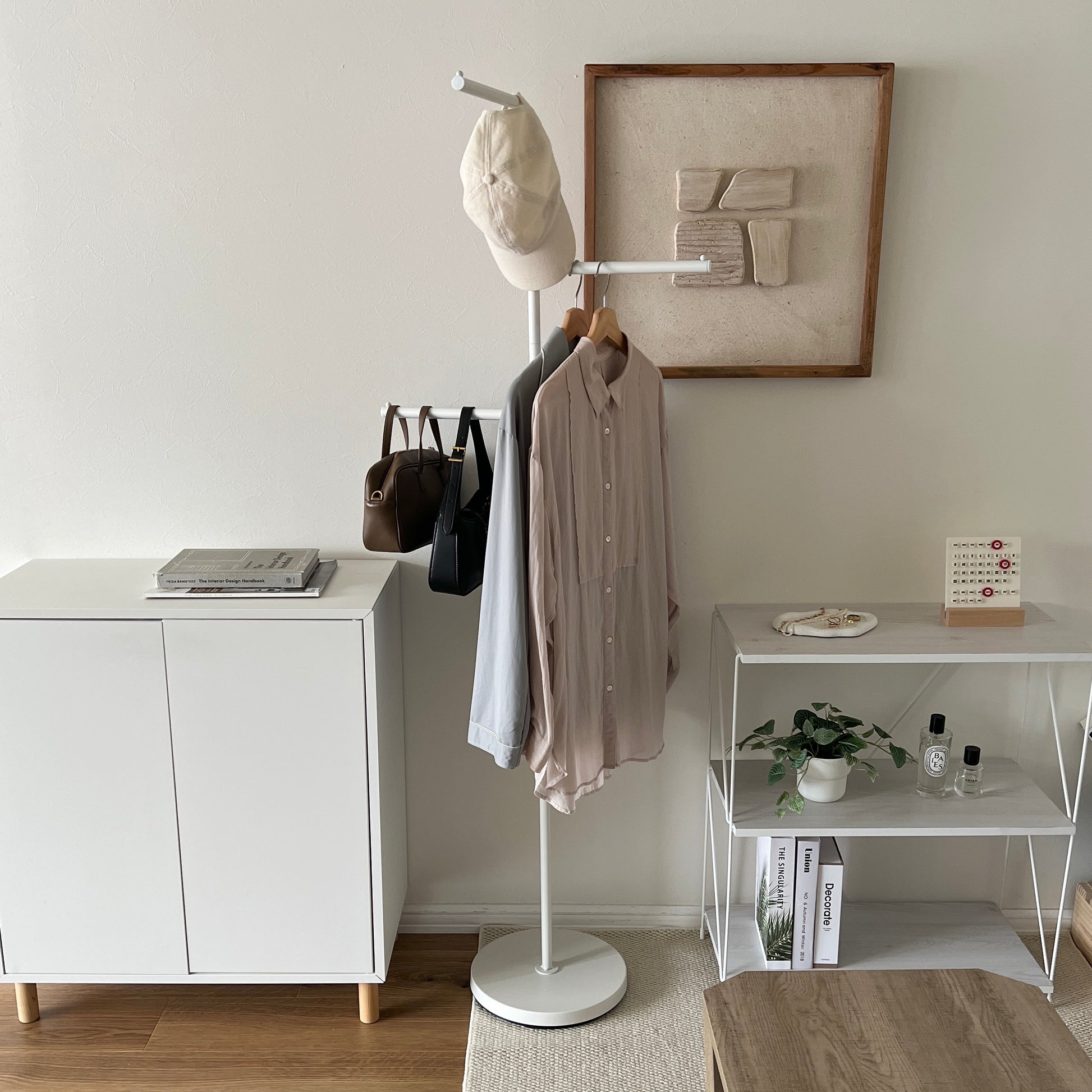 部屋の中で白の回転式ポールハンガーに洋服が飾られている様子