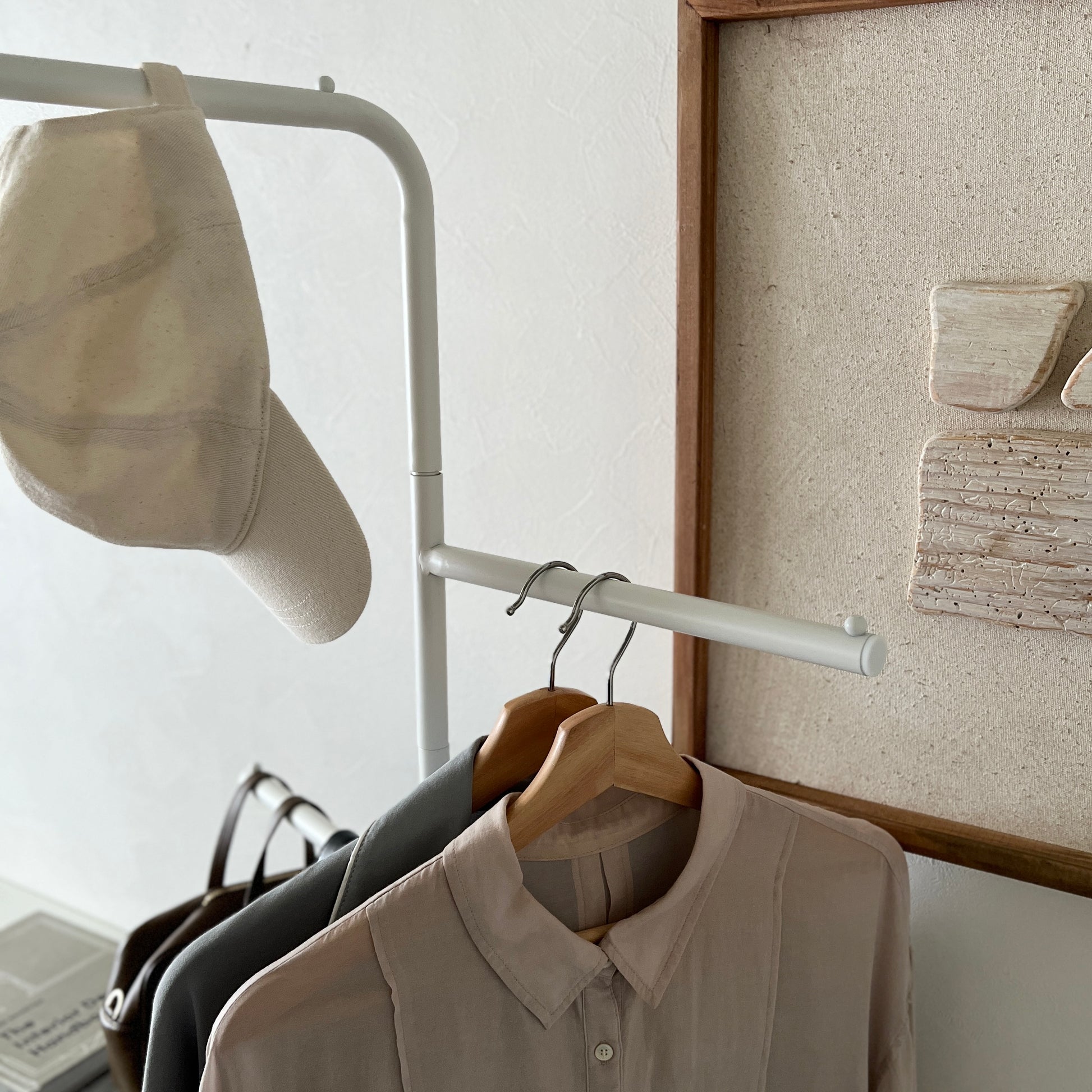 部屋の中で白の回転式ポールハンガーに洋服が飾られている様子