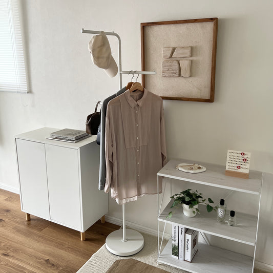 部屋の中で白の回転式ポールハンガーに洋服が飾られている様子