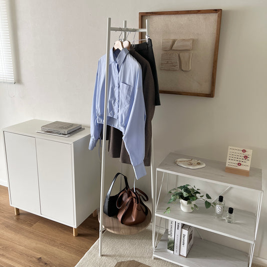 部屋の中で白いコンパクトでスタイリッシュなハンガーラックに洋服がかかっている様子