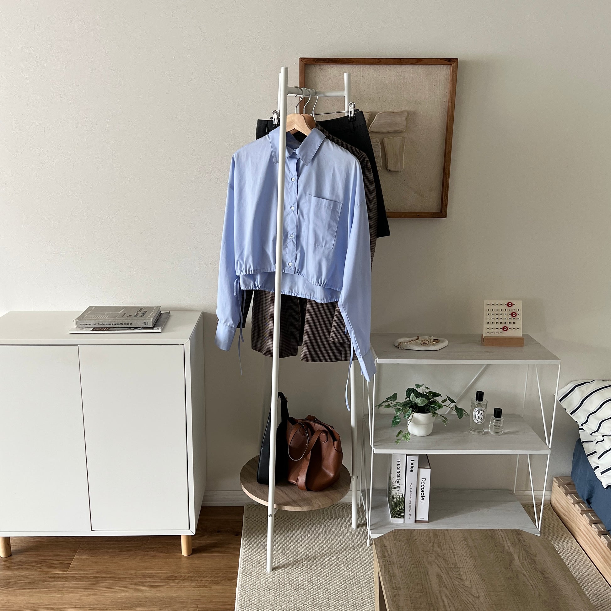 部屋の中で白いコンパクトでスタイリッシュなハンガーラックに洋服がかかっている様子