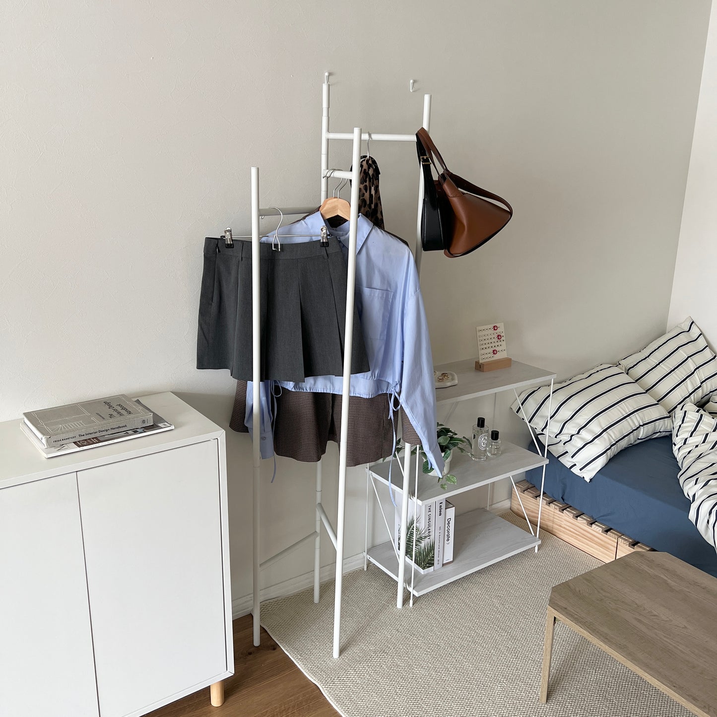部屋の中で折り畳めるスタイリッシュなパーテーションハンガーに洋服やバッグが飾ってある様子