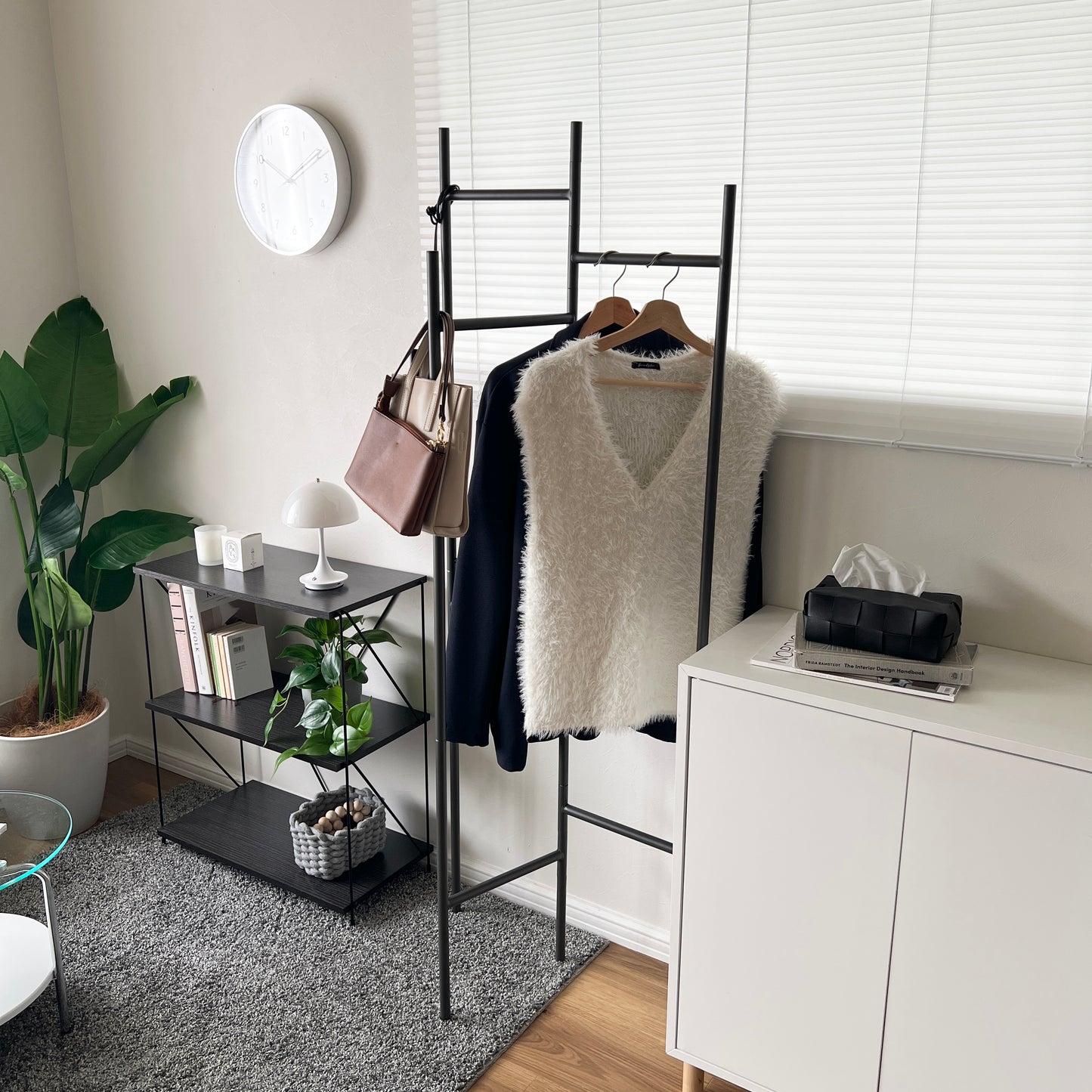 部屋の中で折り畳めるスタイリッシュなパーテーションハンガーに洋服やバッグが飾ってある様子
