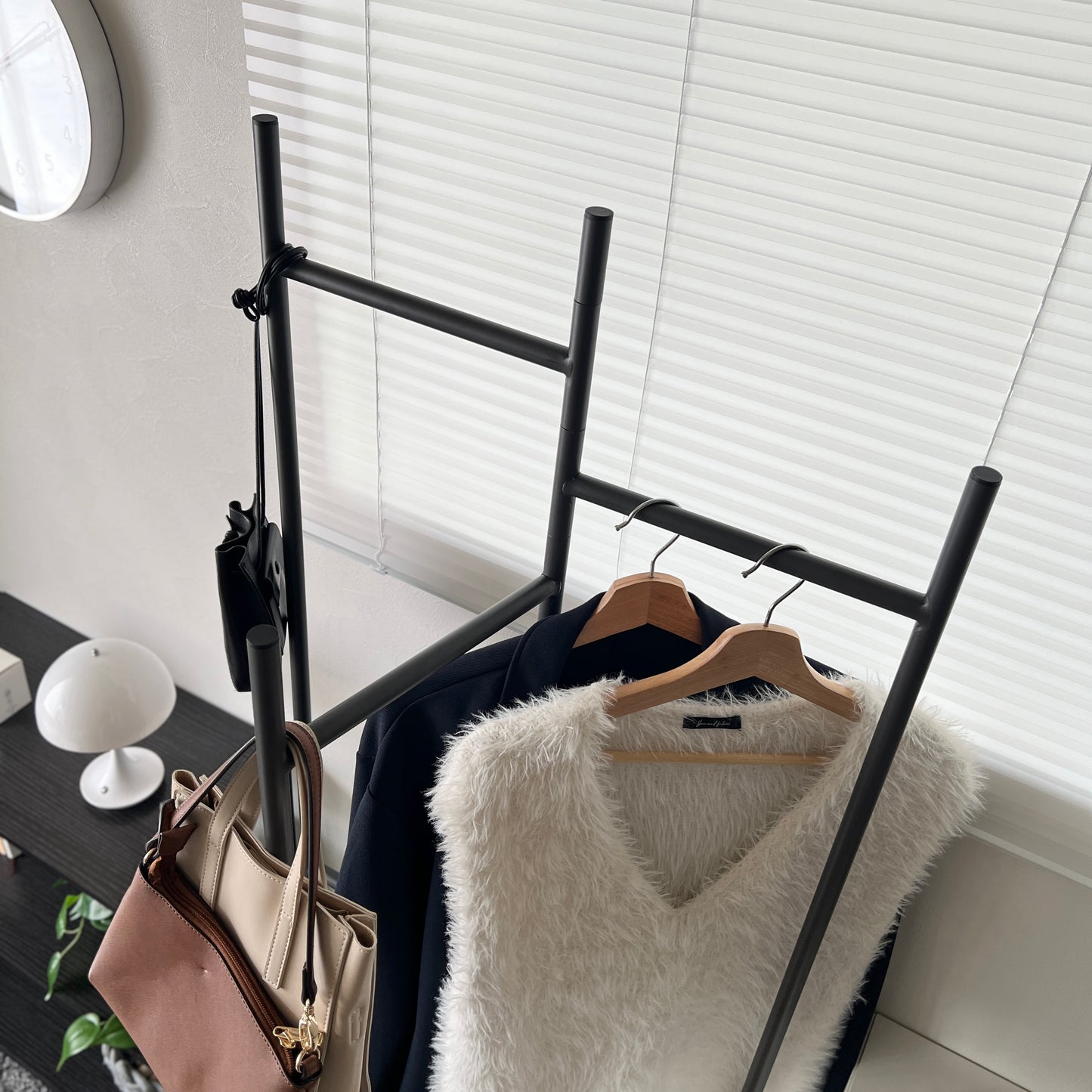 部屋の中で折り畳めるスタイリッシュなパーテーションハンガーに洋服やバッグが飾ってある様子