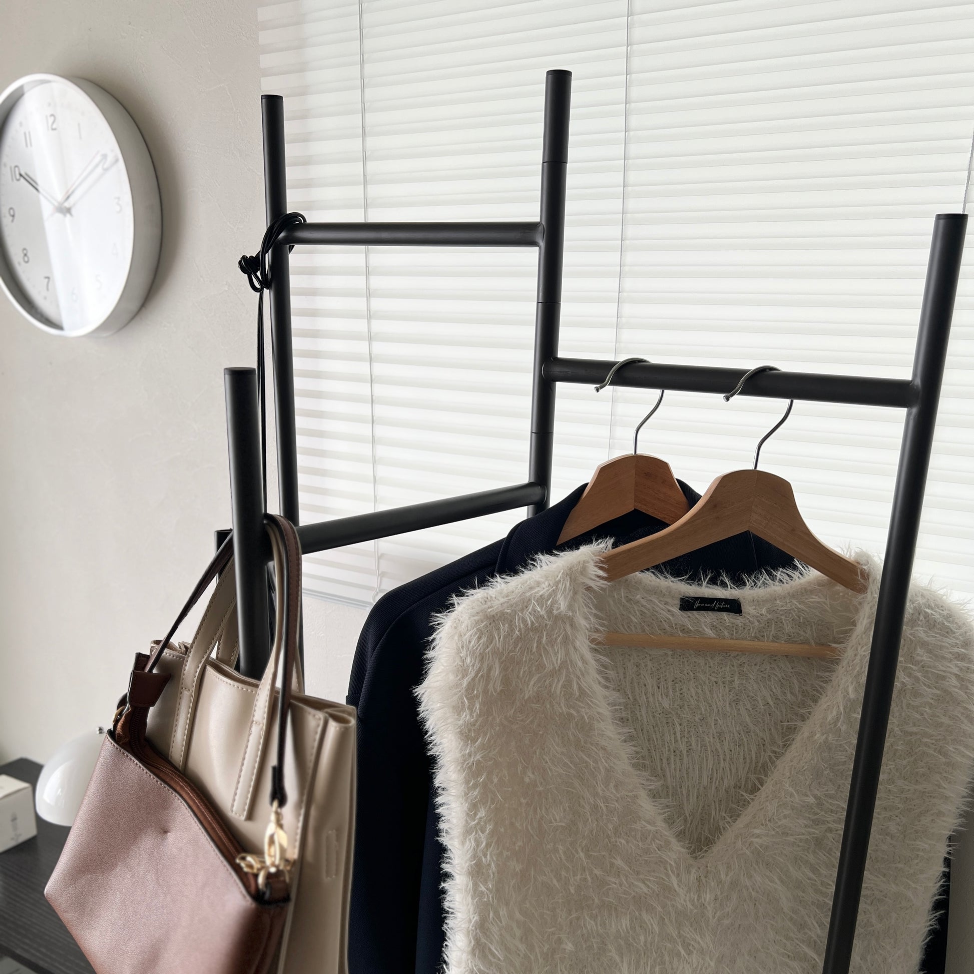 部屋の中で折り畳めるスタイリッシュなパーテーションハンガーに洋服やバッグが飾ってある様子