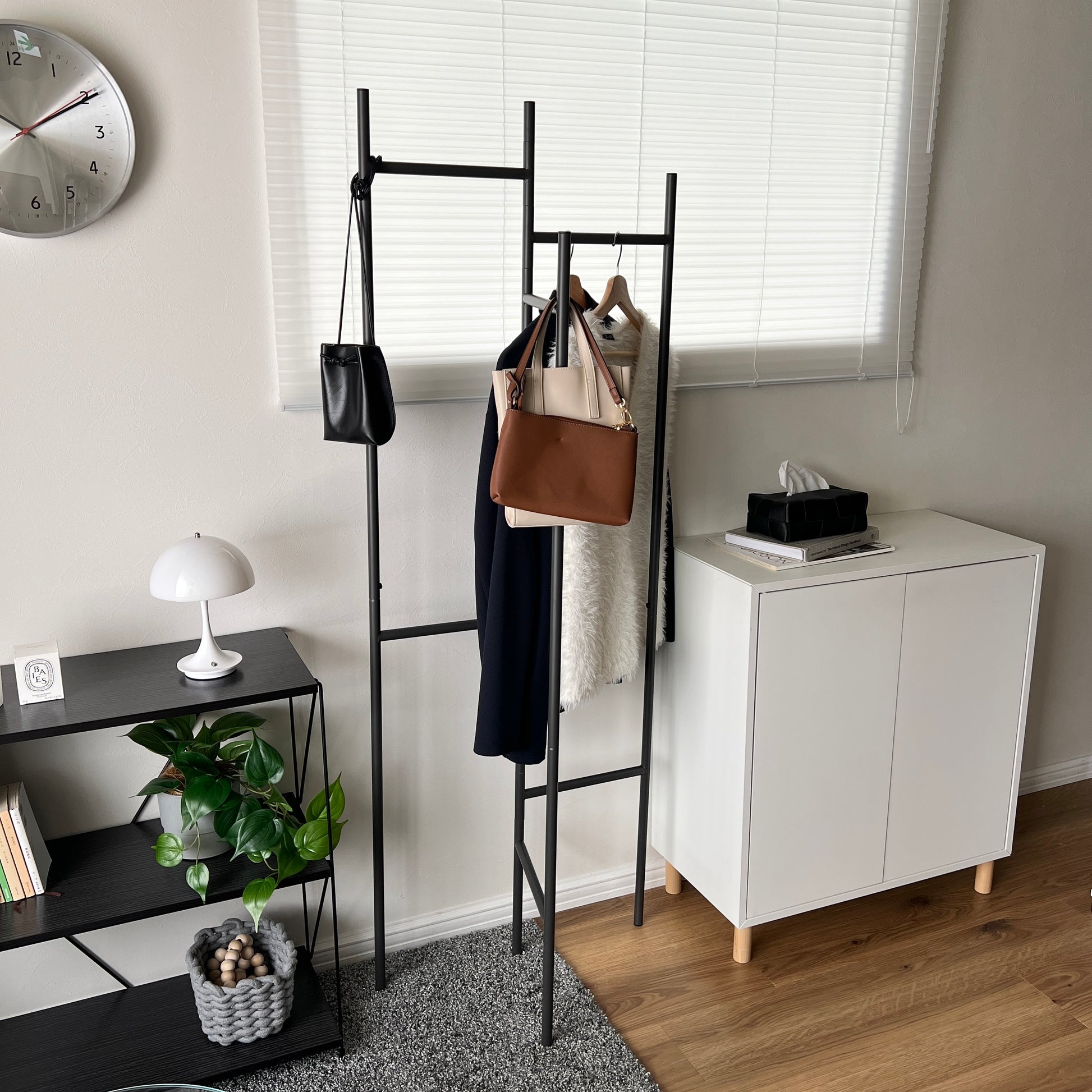 部屋の中で折り畳めるスタイリッシュなパーテーションハンガーに洋服やバッグが飾ってある様子
