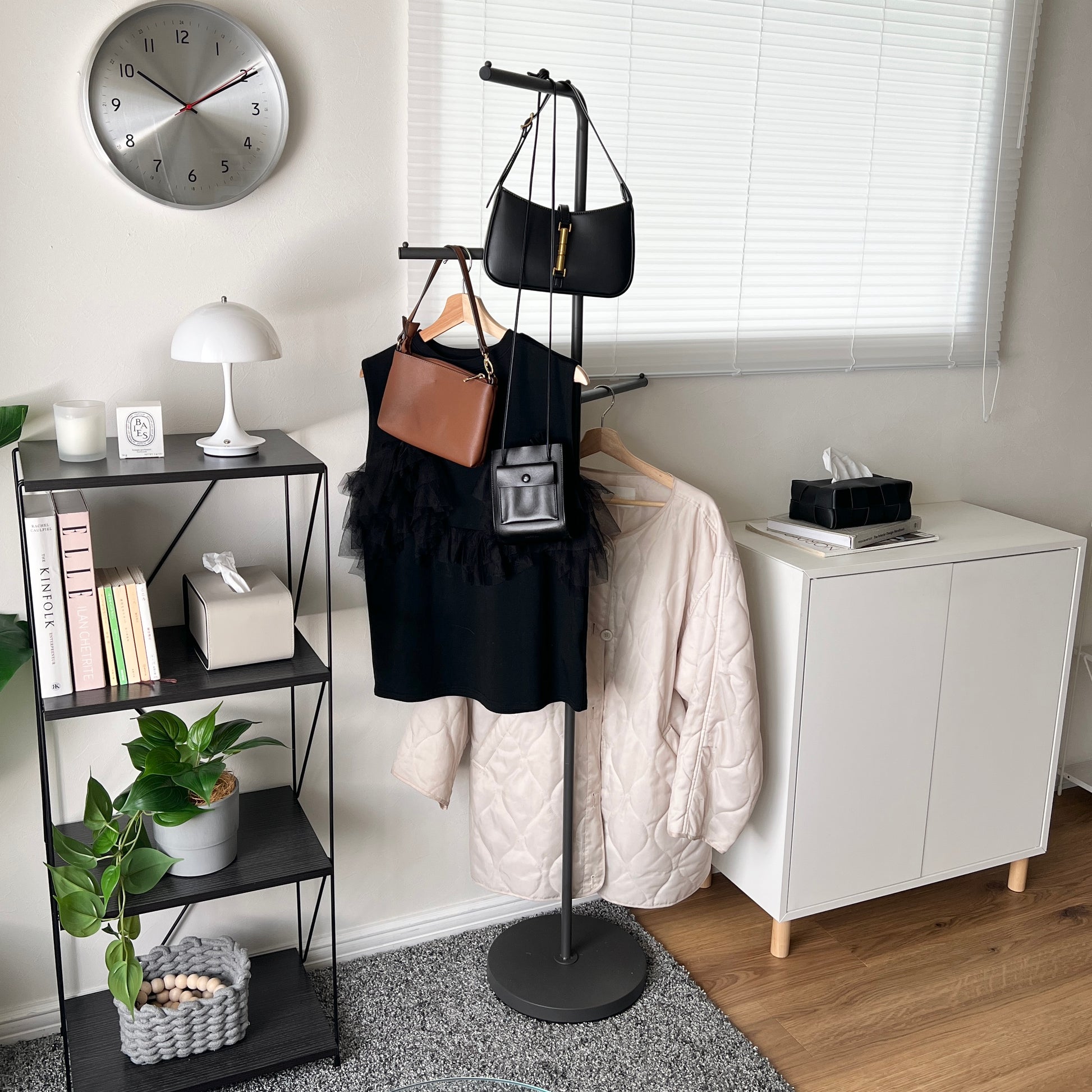 部屋の中で黒の回転式ポールハンガーに洋服が飾られている様子
