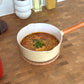 ラーメンが入った黄色の片手鍋がキッチンに置かれている様子