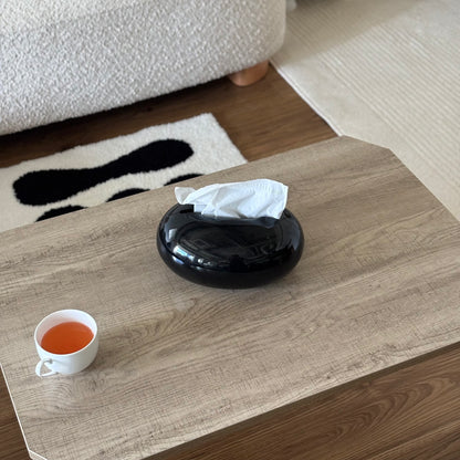 光沢のある丸みを帯びたブラックのティッシュケースをテーブルに置いている様子