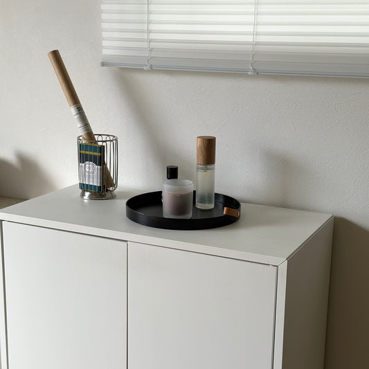 フェイクレザーのラウンド型のトレイに香水やキャンドルが置かれている様子