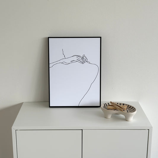 ニュアンスライン後ろ姿が描かれたアートが棚の上に置かれている