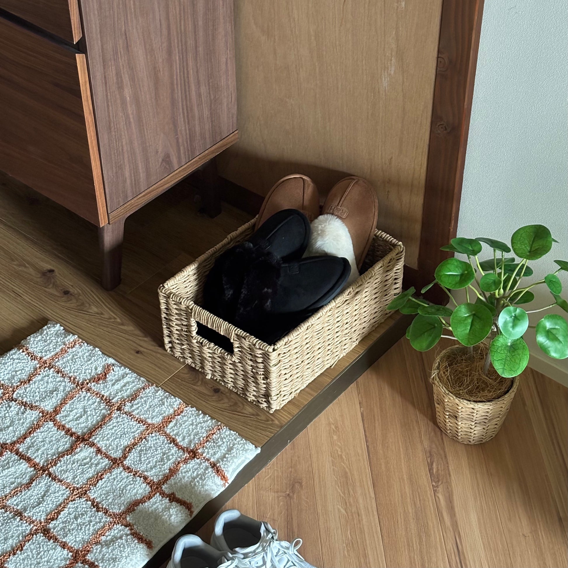 手編みの折り畳み式ペーパーコードバスケットの中にスリッパを入れて玄関に置いている様子