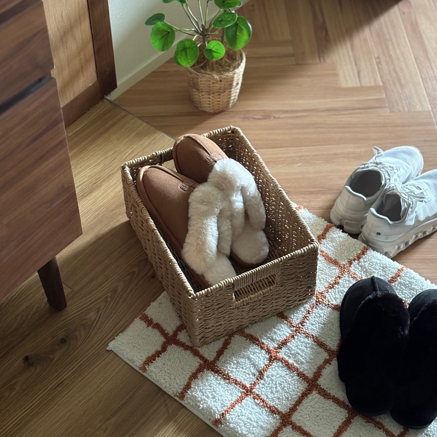 手編みの折り畳み式ペーパーコードバスケットの中にスリッパを入れて玄関に置いている様子